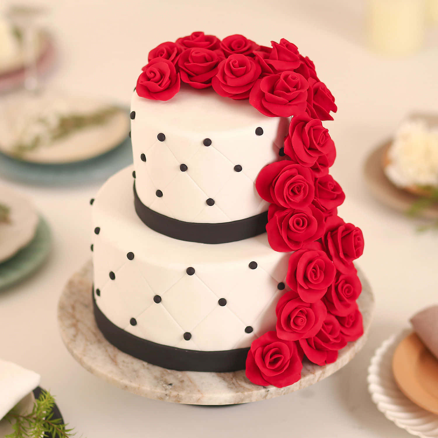 Cake Fondant 桌布 壁紙 — 一個兩層白色翻糖蛋糕，飾有黑色圓點和鮮紅玫瑰瀑布，放在大理石架上。