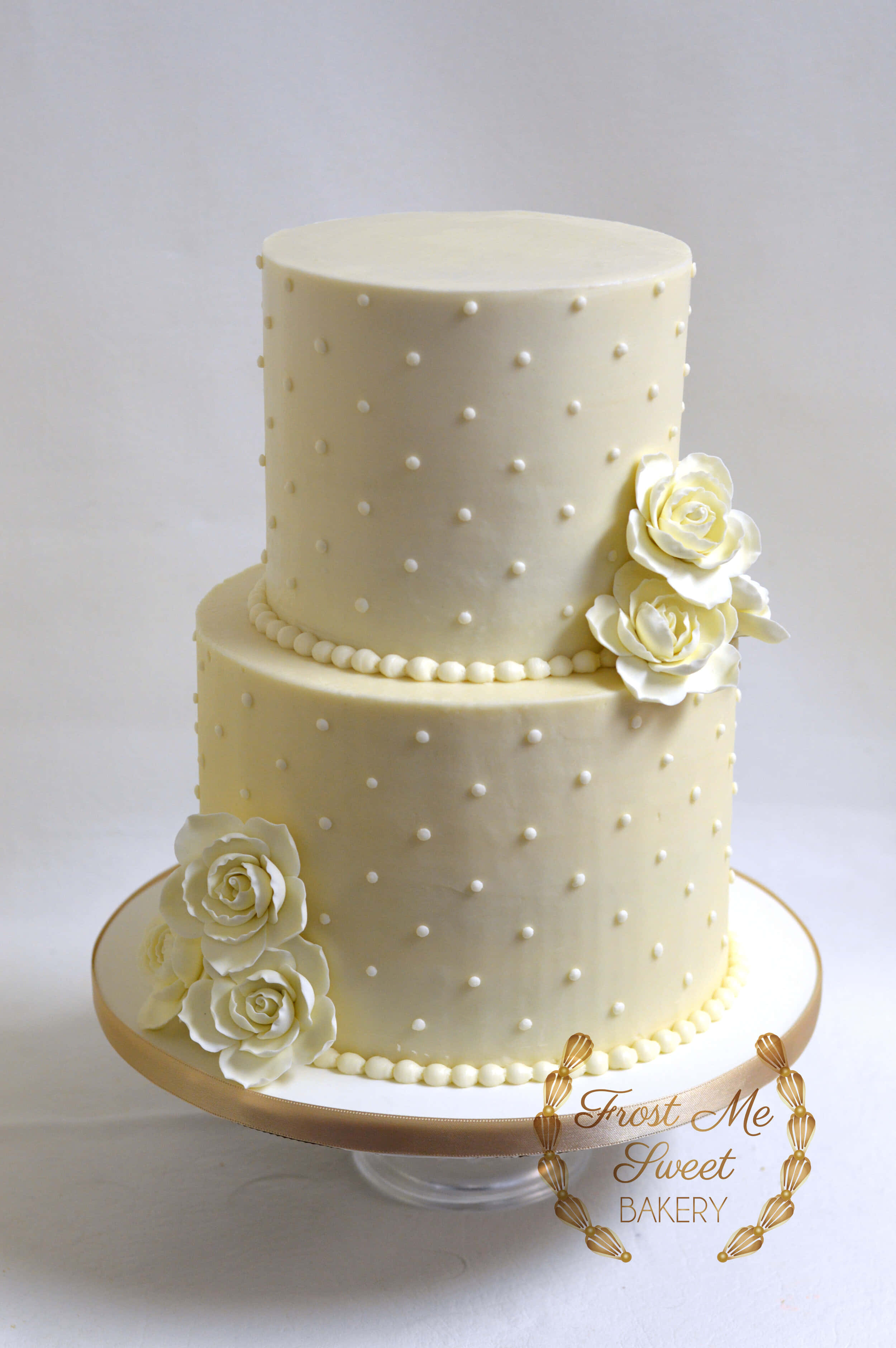 Cake Fondant 桌布 壁紙 — 一個兩層象牙色翻糖婚禮蛋糕，飾以精緻的糖玫瑰和圓點圖案，優雅地放置在金色蛋糕架上。