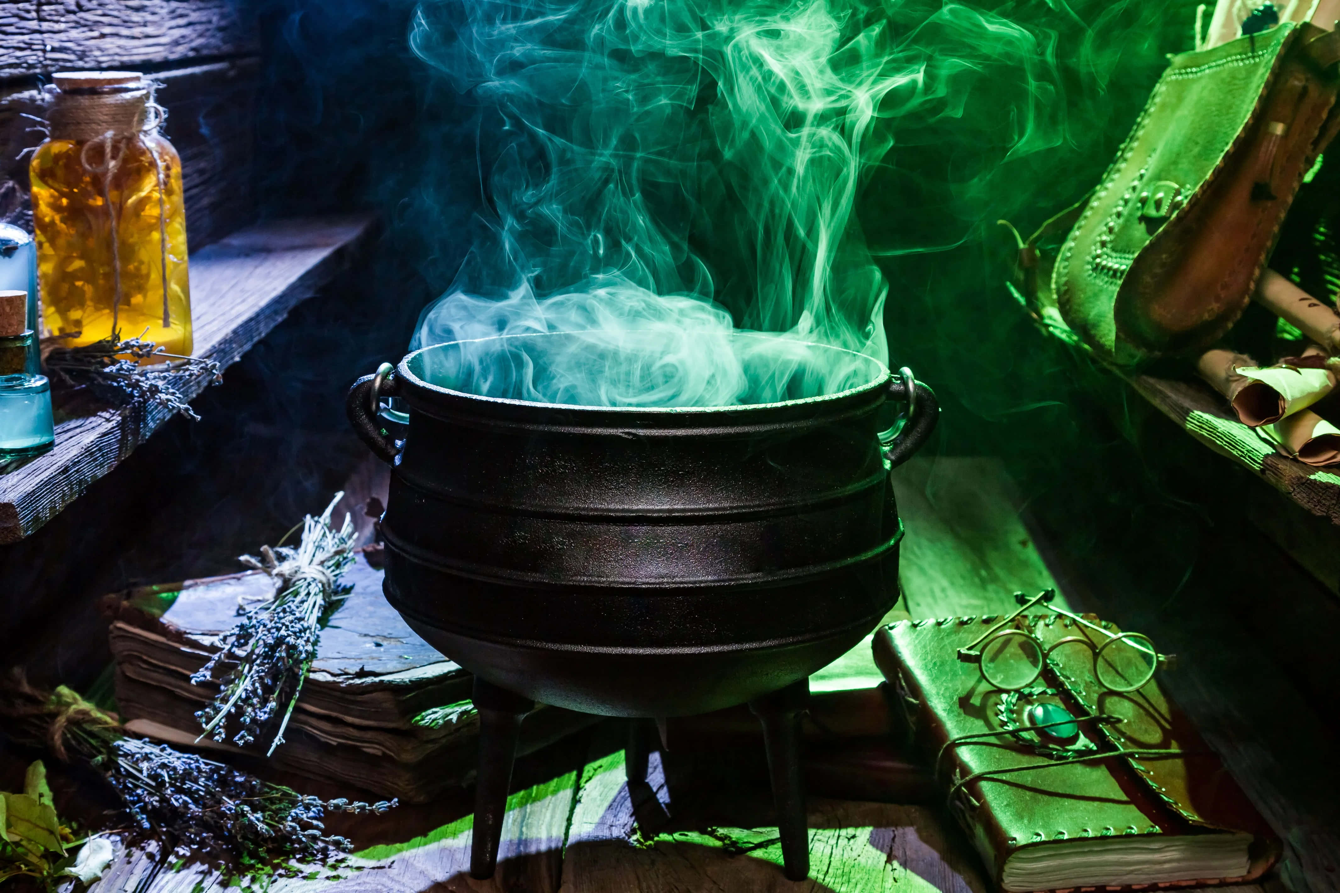 cauldron 桌布 壁紙 — 一個冒泡的黑色大鍋在昏暗的女巫工作室中散發出詭異的綠色煙霧，周圍擺滿了藥水和古籍。