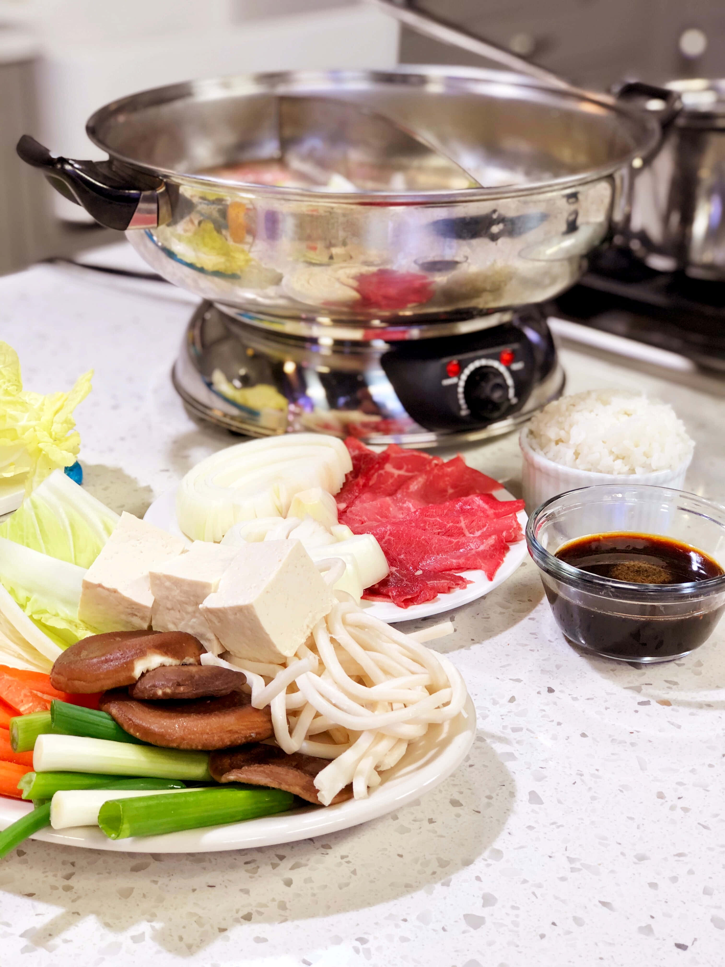 Healthy Food 桌布 壁紙 — 一個冒煙的熱鍋，旁邊的盤子上有薄切牛肉和新鮮蔬菜，還有飯和蘸醬，放在廚房檯面上。