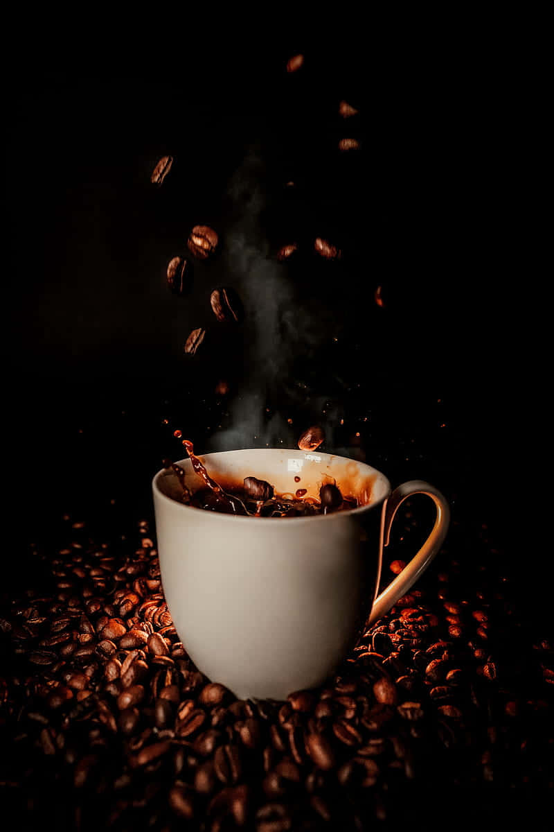Coffee Aesthetic 桌布 壁紙 — 一個冒煙的白色咖啡杯，周圍散落著咖啡豆，豆子懸浮在空中，背景為黑色。