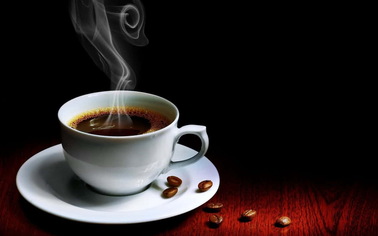 Black Coffee 桌布 壁紙 — 一個冒煙的白色咖啡杯放在碟子上，碟上有散落的咖啡豆，置於黑色背景前的深色木質表面上。