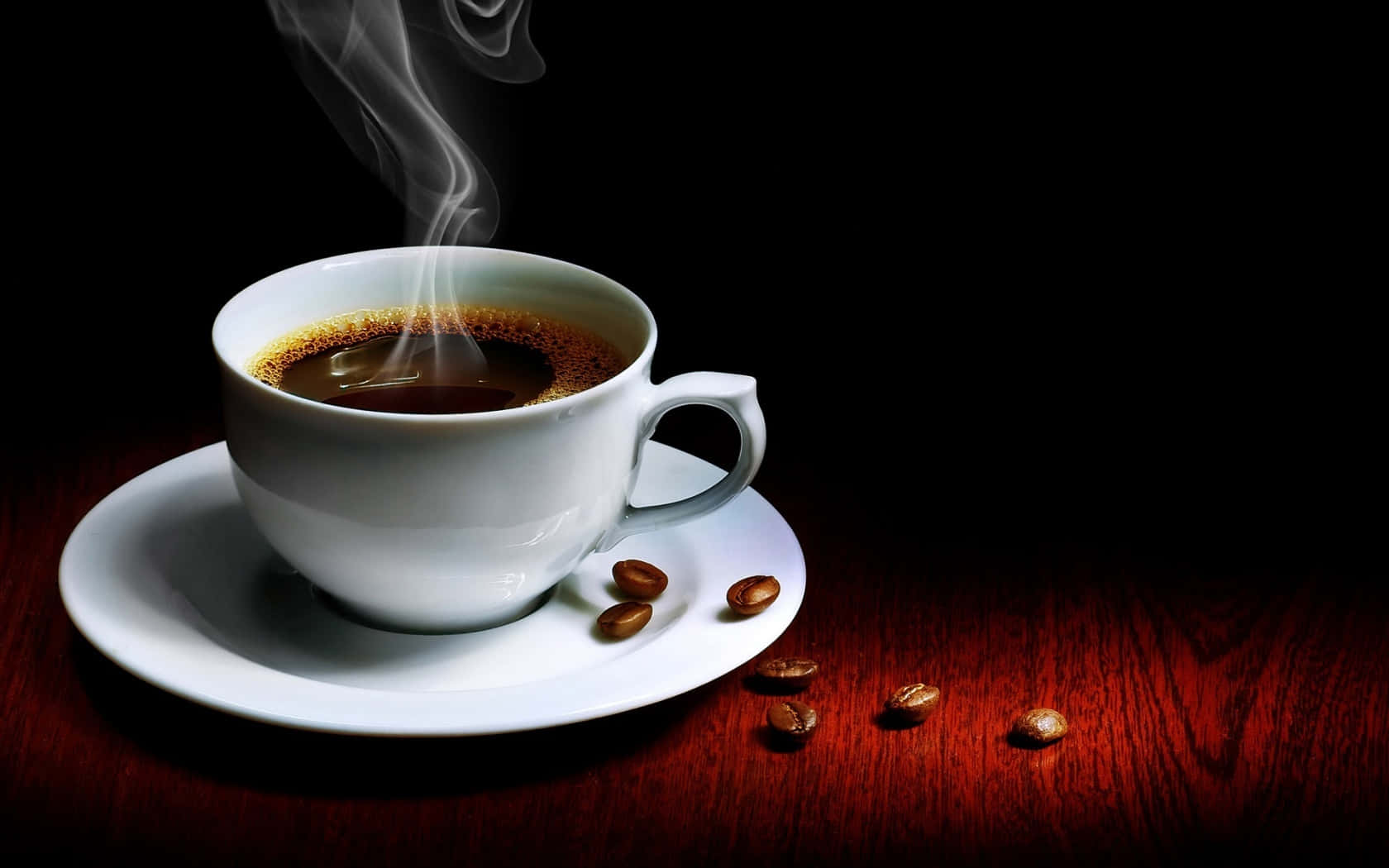 Coffee Cup 桌布 壁紙 — 一個冒煙的白色咖啡杯放在碟子上，碟子周圍散落著咖啡豆，置於黑色背景前的深色木桌上。
