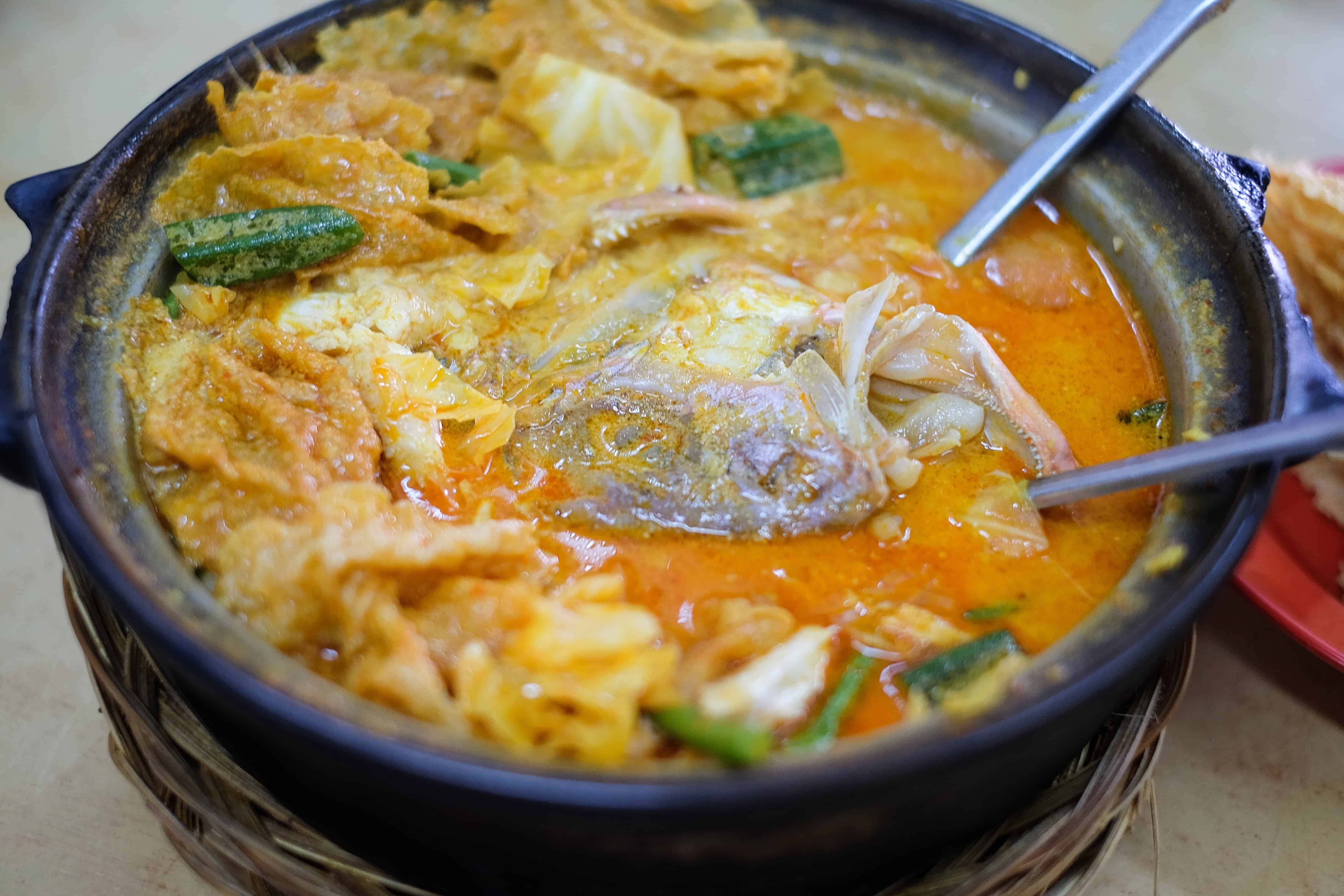 Food Photography 桌布 壁紙 — 一個冒煙的陶鍋，裝滿濃郁的橙色魚咖哩，上面放著炸豆腐和綠色秋葵。