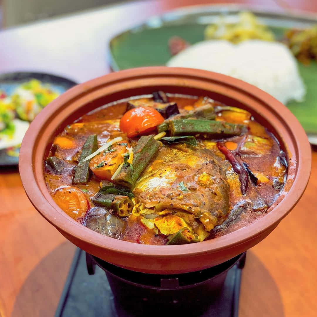 Food Photography 桌布 壁紙 — 一個冒著熱氣的砂鍋，裡面裝滿了濃郁香料調味的魚咖哩和色彩繽紛的蔬菜，準備上桌。