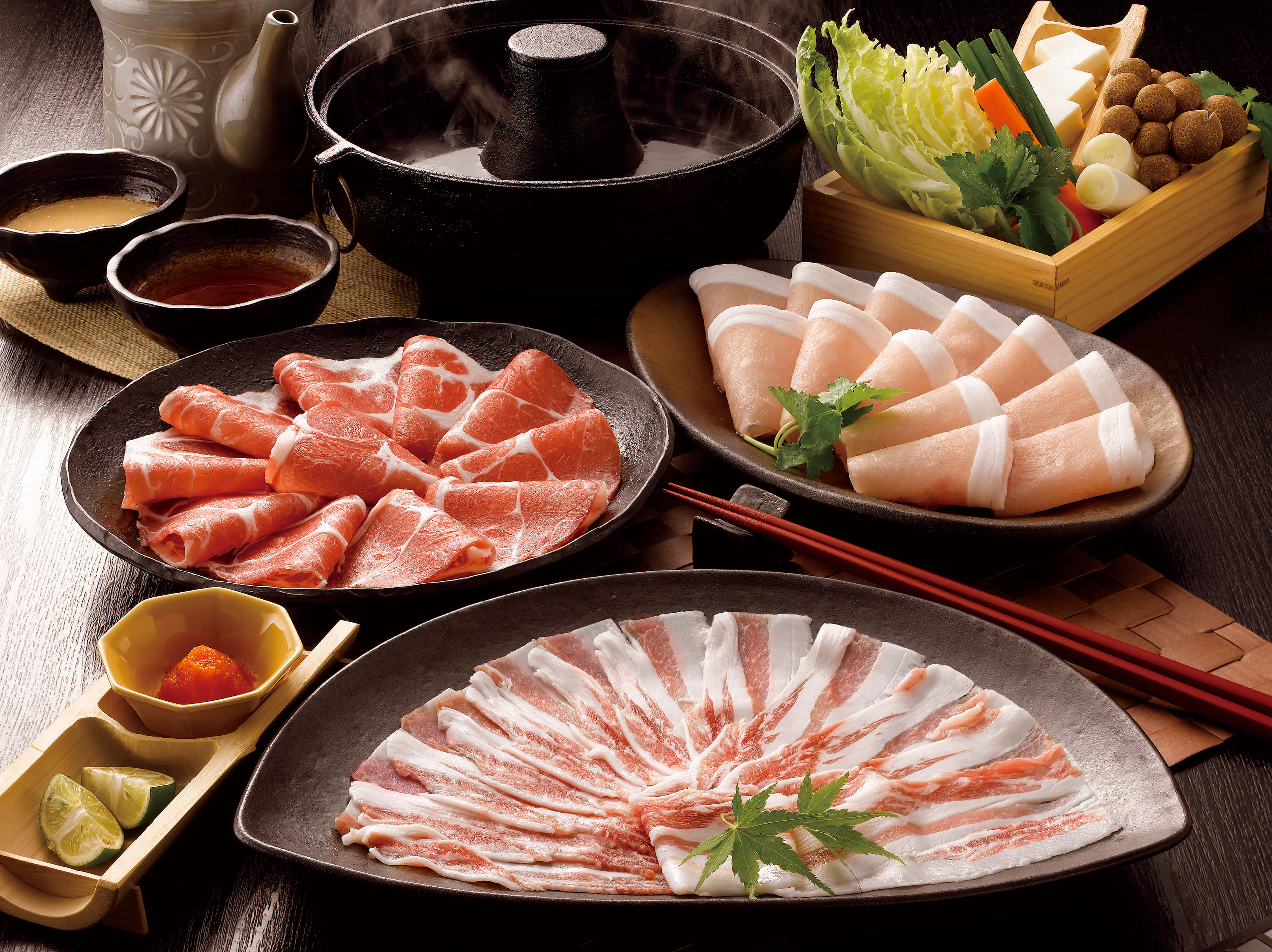 meat 桌布 壁紙 — 一個冒著熱氣的鍋，周圍放著一盤盤切得薄薄的生豬腩肉和各種新鮮蔬菜，準備烹調。