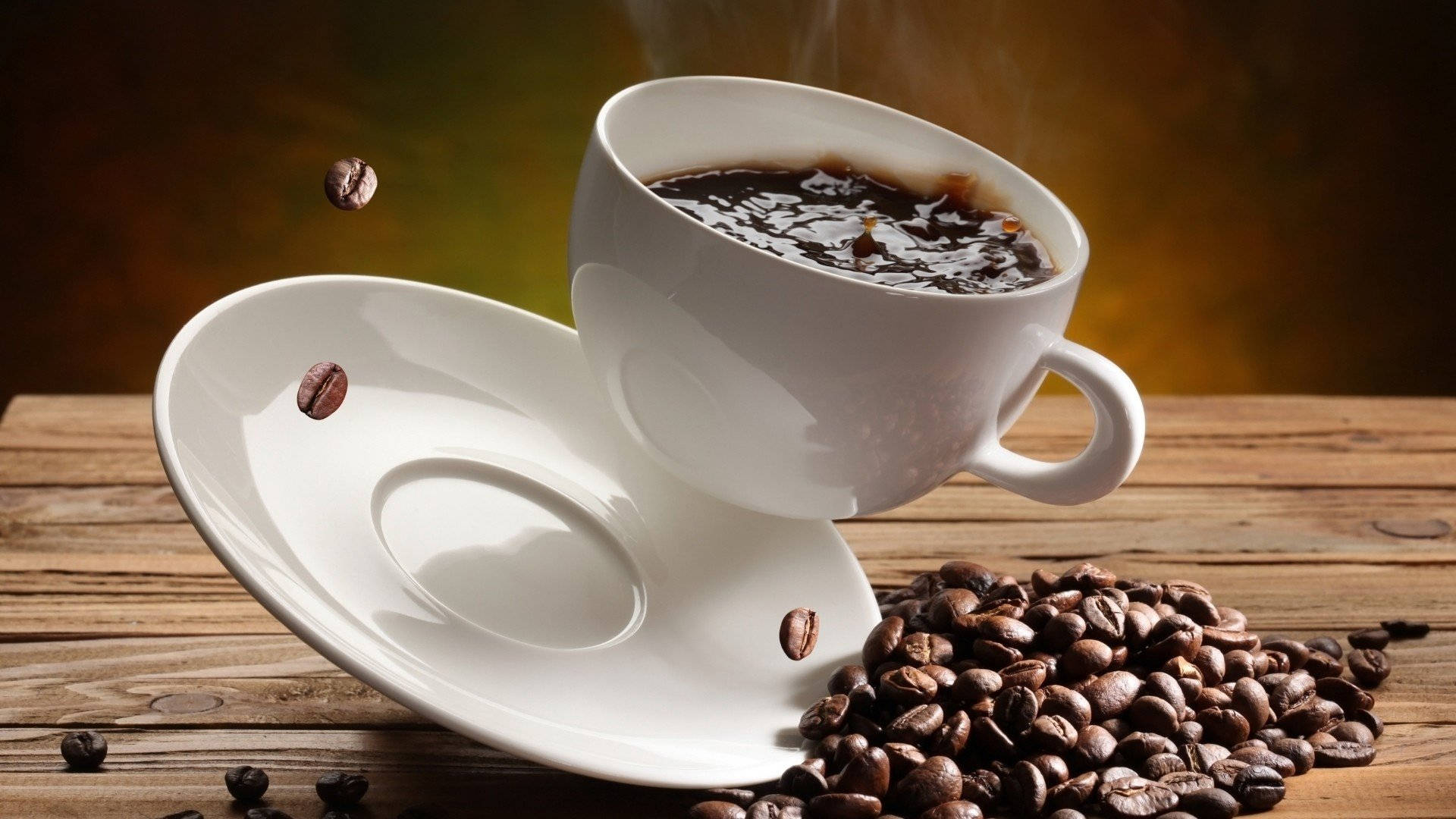 Coffee Aesthetic 桌布 壁紙 — 一個冒著蒸氣的白咖啡杯傾斜在碟子上，烘焙過的咖啡豆散落在質樸的木桌上。