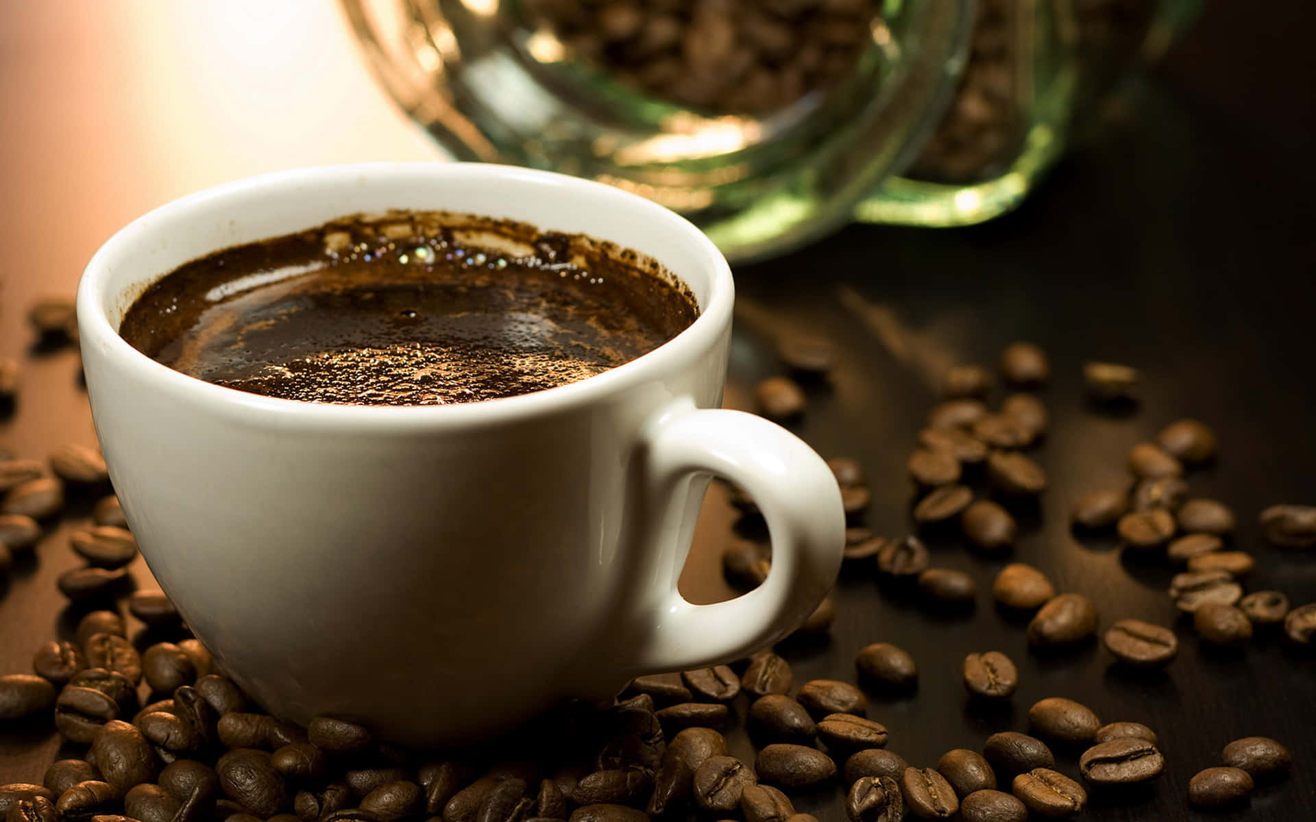 Coffee Cup 桌布 壁紙 — 一個冒著蒸氣的白色咖啡杯，周圍環繞著烘焙咖啡豆，放在深色木質表面上，背景有一個玻璃罐。