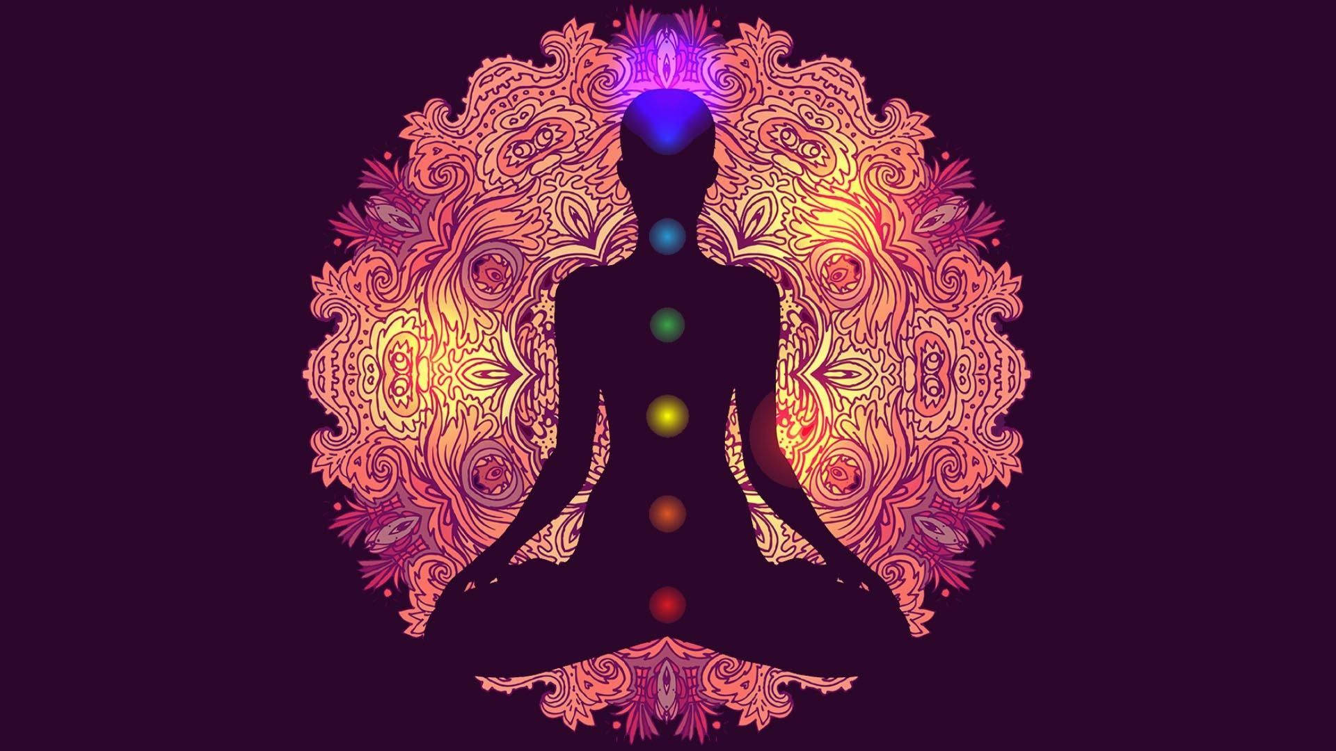 瑜珈 桌布 壁紙 — 一個冥想人物的剪影，帶有發光的脈輪，周圍環繞著溫暖色調的複雜曼陀羅圖案。