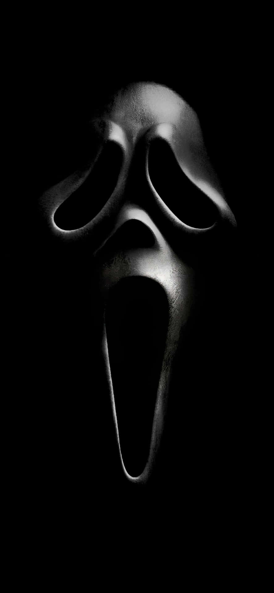 Aesthetic iPhone Horror 桌布 壁紙 — 一個冰冷照明的白色鬼面面具在漆黑虛空中發光，喚起純粹的恐怖。