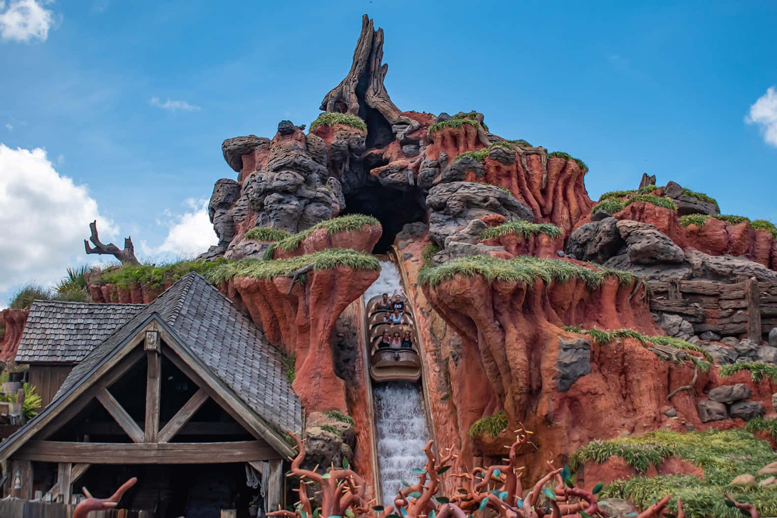 Splash Mountain 桌布 壁紙 — 一個刺激的水上遊樂設施在晴朗藍天下沿著一個巨大紅色岩石形成的巨型樹樁形狀俯衝而下。