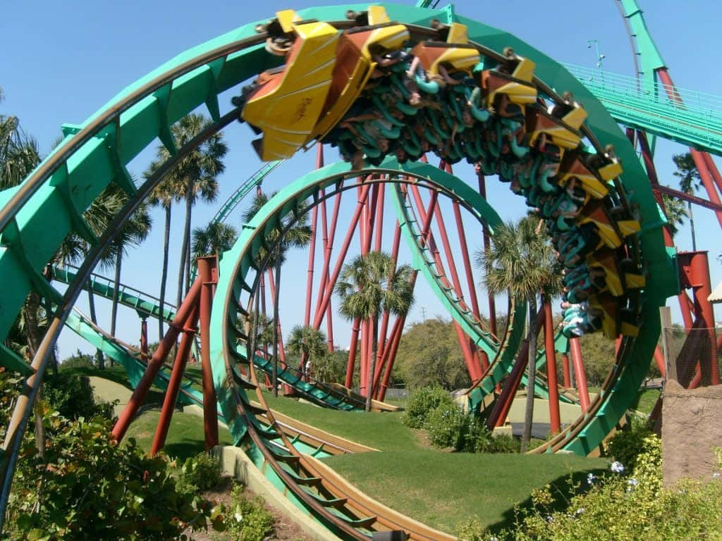 Roller Coaster 桌布 壁紙 — 一個刺激的雲霄飛車，乘客在鮮綠色和紅色的迴圈中倒掛，背景是清澈的藍天。