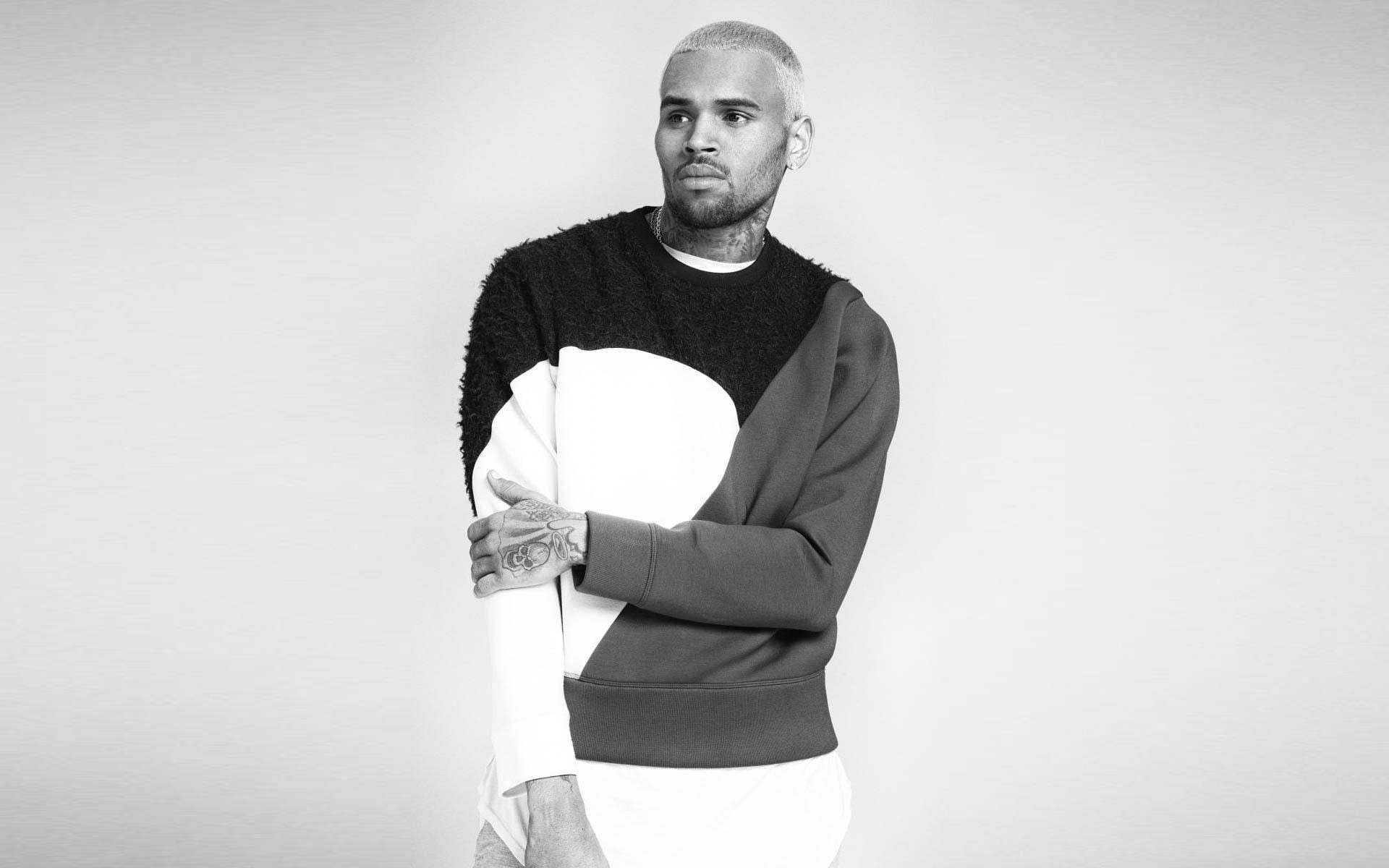 Chris Brown 桌布 壁紙 — 一個剃光頭及有刺青的男人，在純色背景前穿著一件大膽的黑白拼色毛衣。