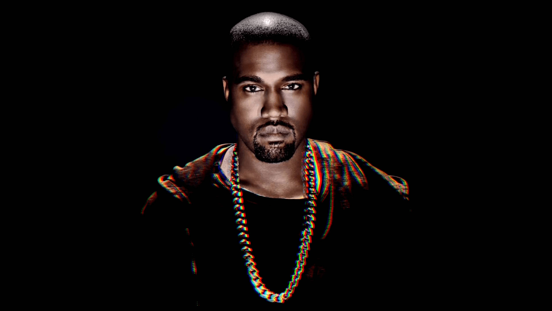 Kanye West 桌布 壁紙 — 一個剃光頭和留鬍子的男人，穿著色彩繽紛的鏈條和圖案襯衫，在黑色背景下凝視著。