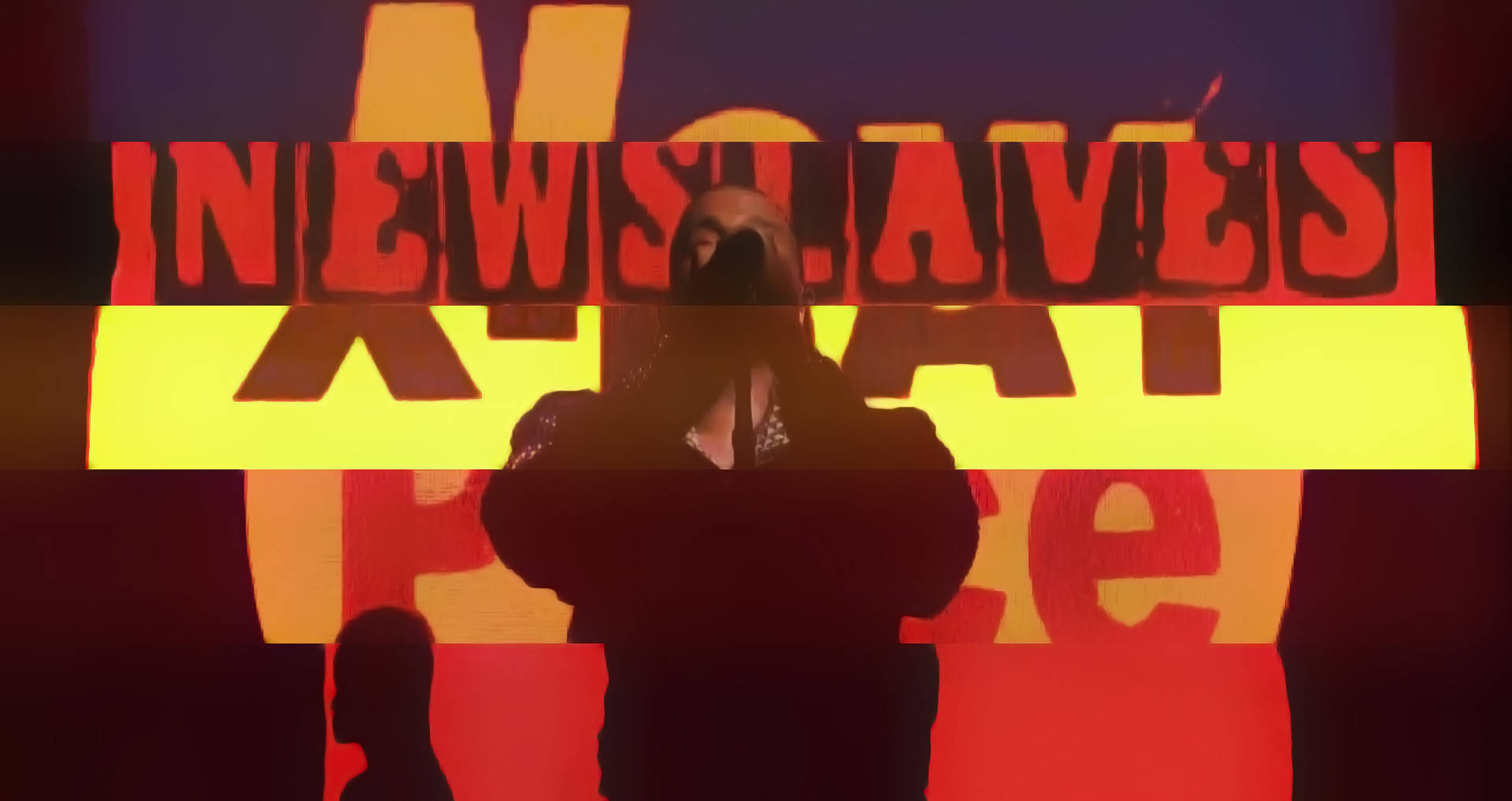Kanye 桌布 壁紙 — 一個剪影人物站在大膽的紅色和黃色 'NEW SLAVES' 文字背景前，場景昏暗且對比強烈。