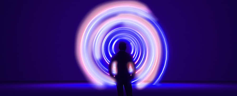Time Travel 桌布 壁紙 — 一個剪影人物站在深紫色背景前，面對著由藍色和粉紅色光軌組成的發光螺旋。