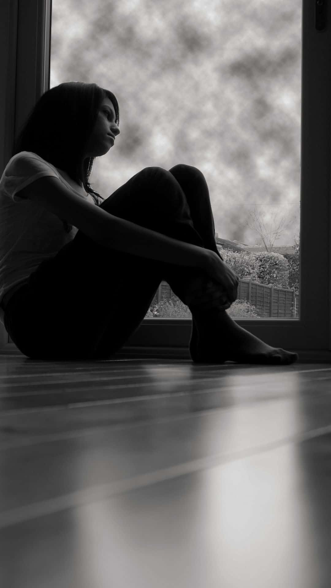 Woman 桌布 壁紙 — 一個剪影女人赤腳坐在木地板上，凝視窗外多雲的天空。