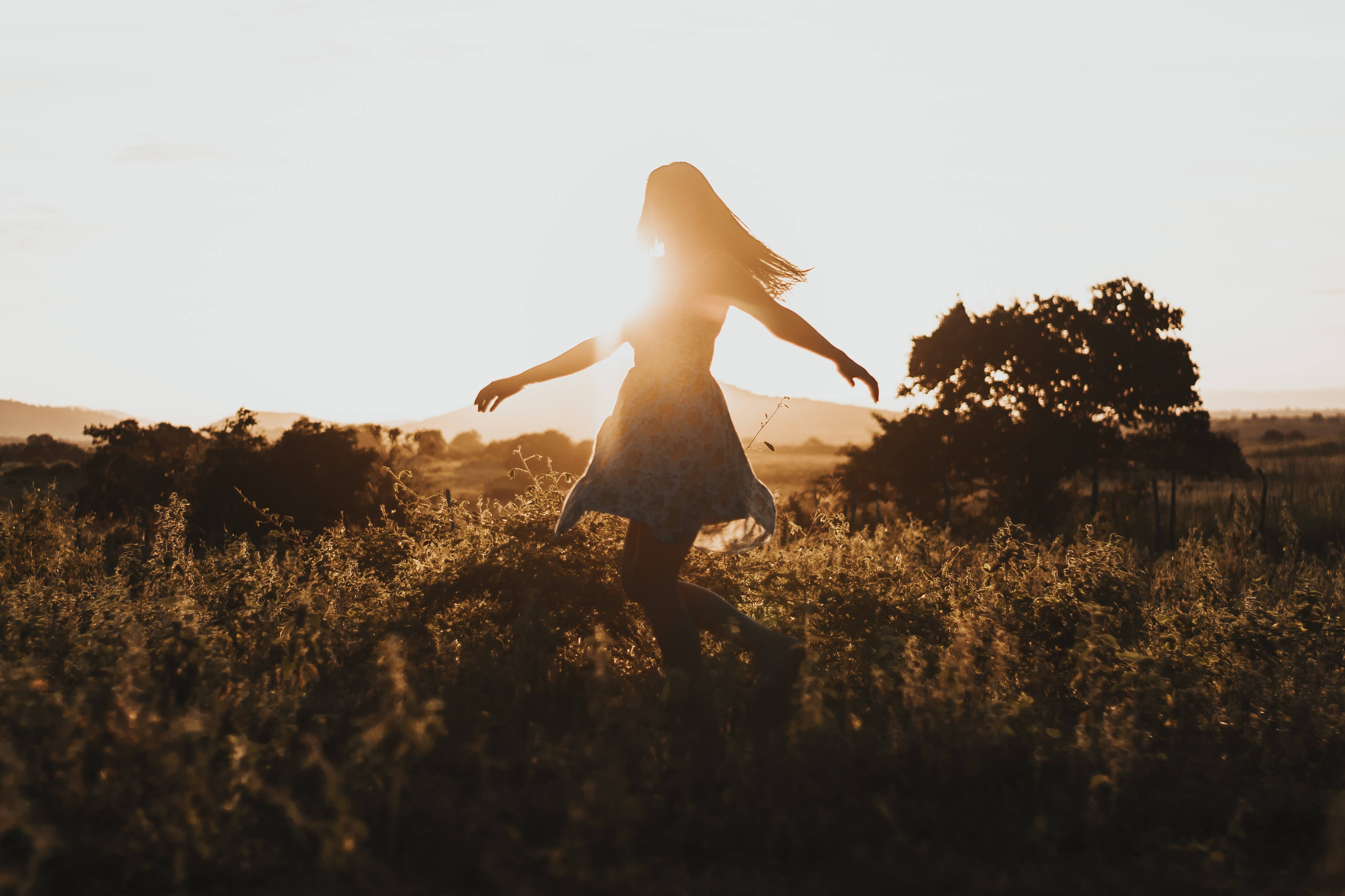 Silhouette 桌布 壁紙 — 一個剪影女性在高的草叢中快樂地奔跑，金色的夕陽光芒在她身後閃耀。