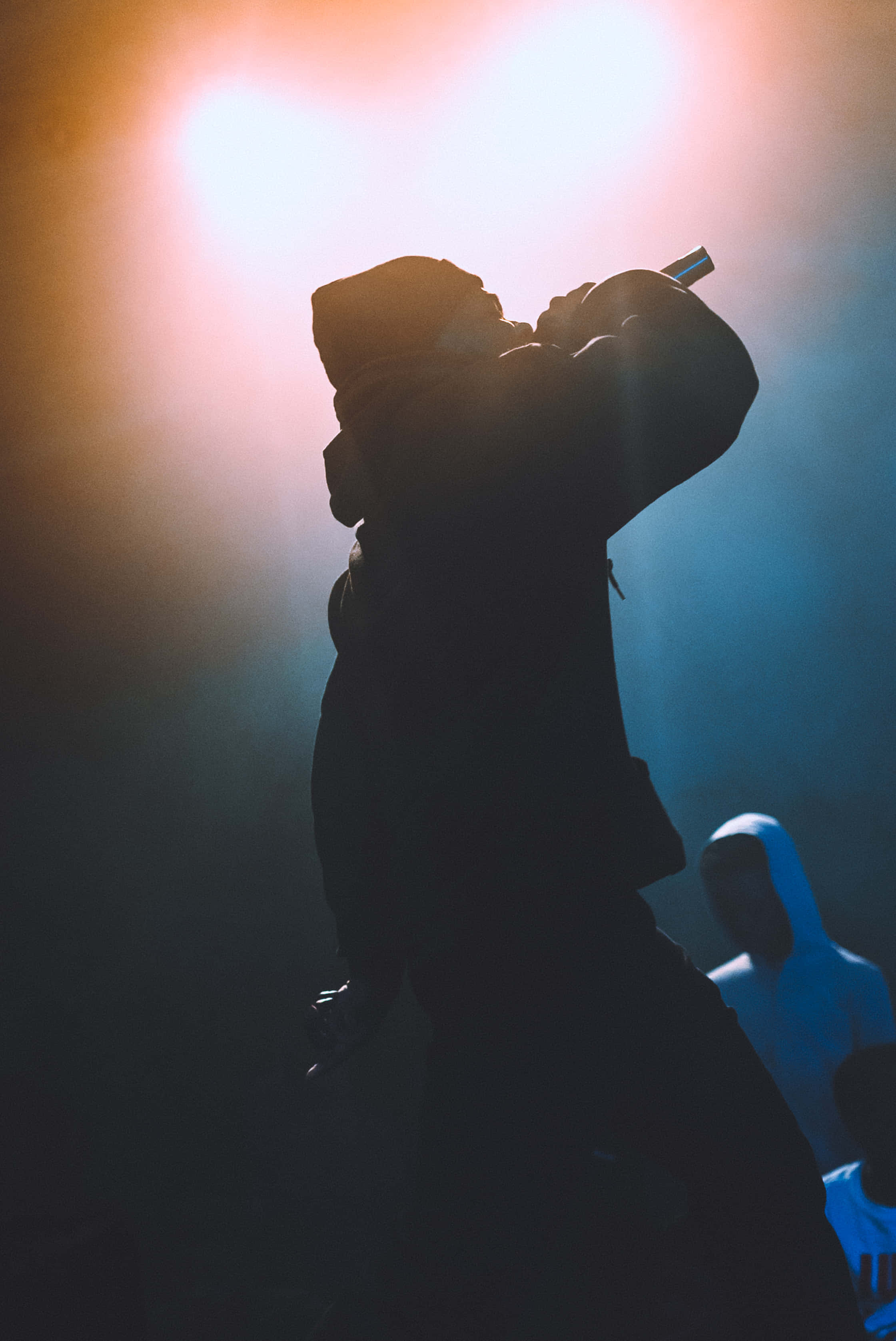 Rap Aesthetic 桌布 壁紙 — 一個剪影說唱歌手在戲劇性的舞台燈光下表演，帶有朦朧的氛圍光芒。
