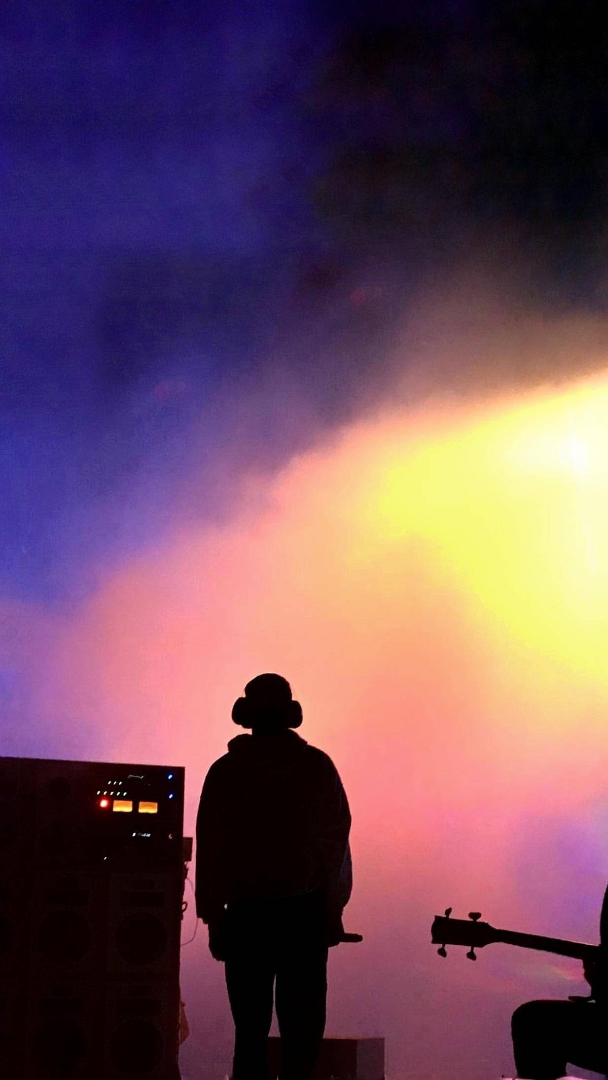 Frank Ocean 桌布 壁紙 — 一個剪影音樂家站在充滿活力的紫色和黃色舞台燈光漸變前，煙霧繚繞。