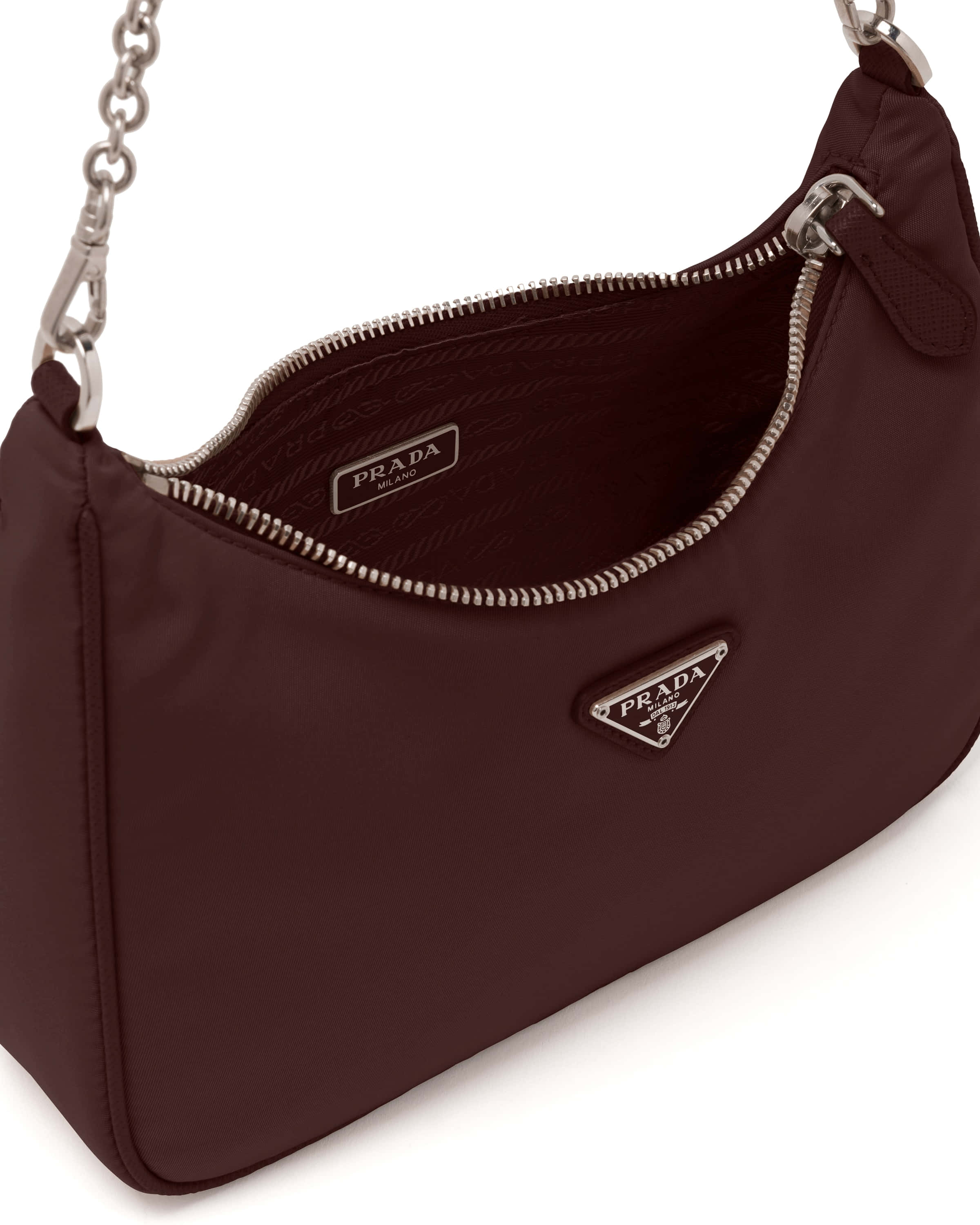 Prada 桌布 壁紙 — 一個勃艮第色Prada手提包，配有銀色鏈條肩帶和標誌牌，在白色背景上打開展示。