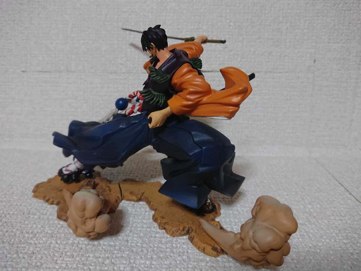 Rai-dei The Blade 桌布 壁紙 — 一個動態動漫公仔，身穿橙色和藍色長袍的劍士在岩石底座上進行動作，帶有煙霧效果。