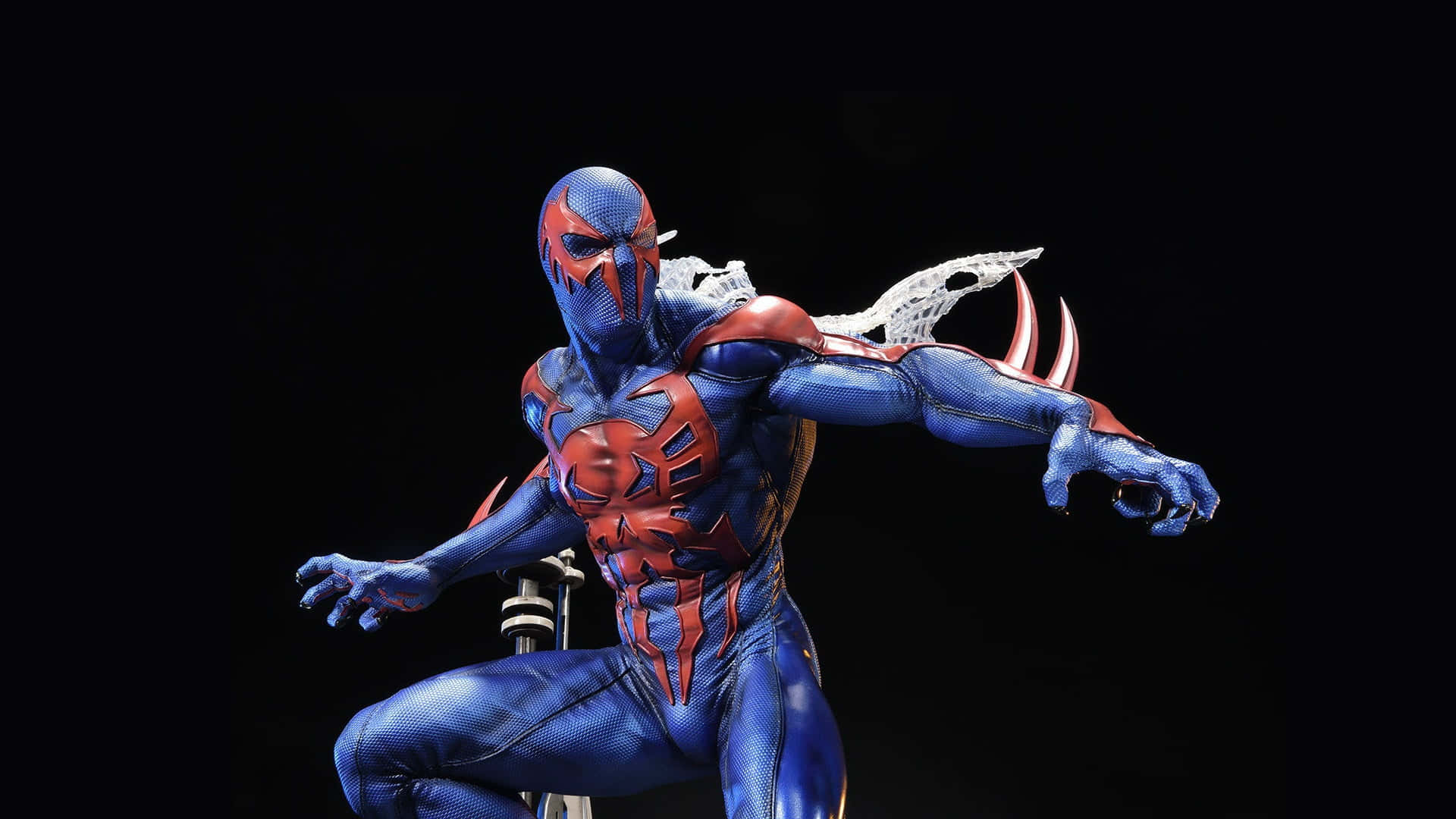 Spider Man 2099 桌布 壁紙 — 一個動態的藍色和紅色蜘蛛人公仔，帶有白色蛛網翅膀，以英雄姿態蹲伏在黑色背景前。