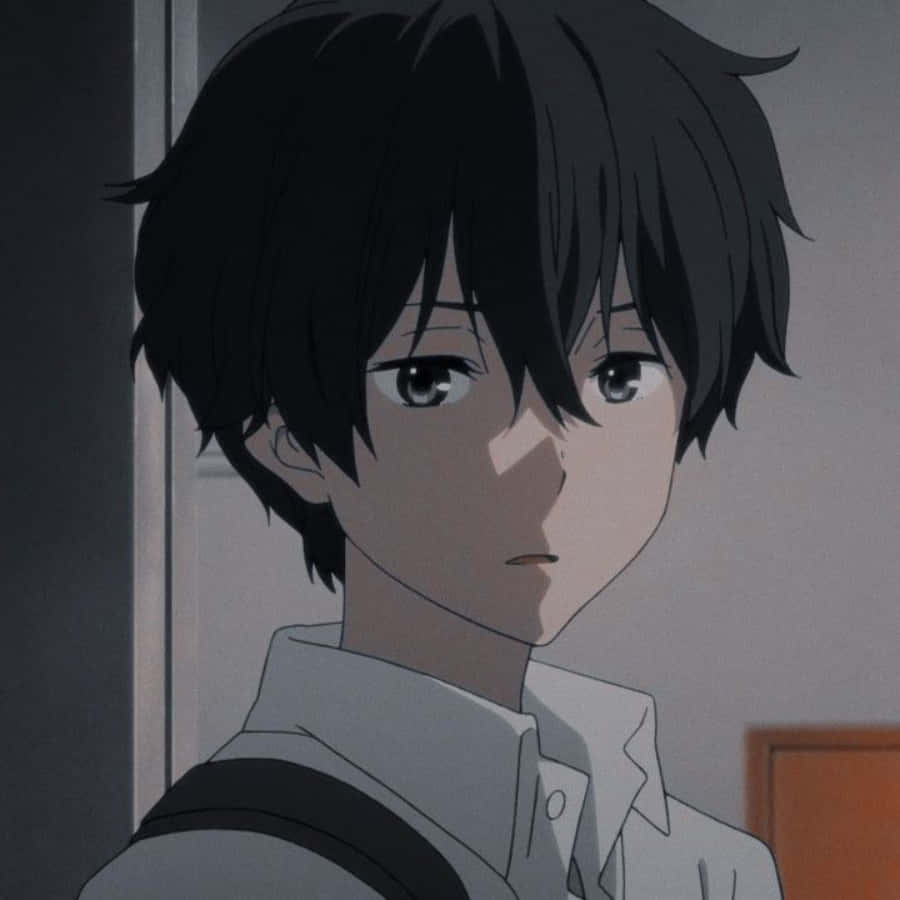 Aesthetic Anime Profile 桌布 壁紙 — 一個動漫男孩的近距離特寫，他有一頭凌亂的黑髮和嚴肅的眼神，在昏暗的房間裡稍微看向鏡頭外。