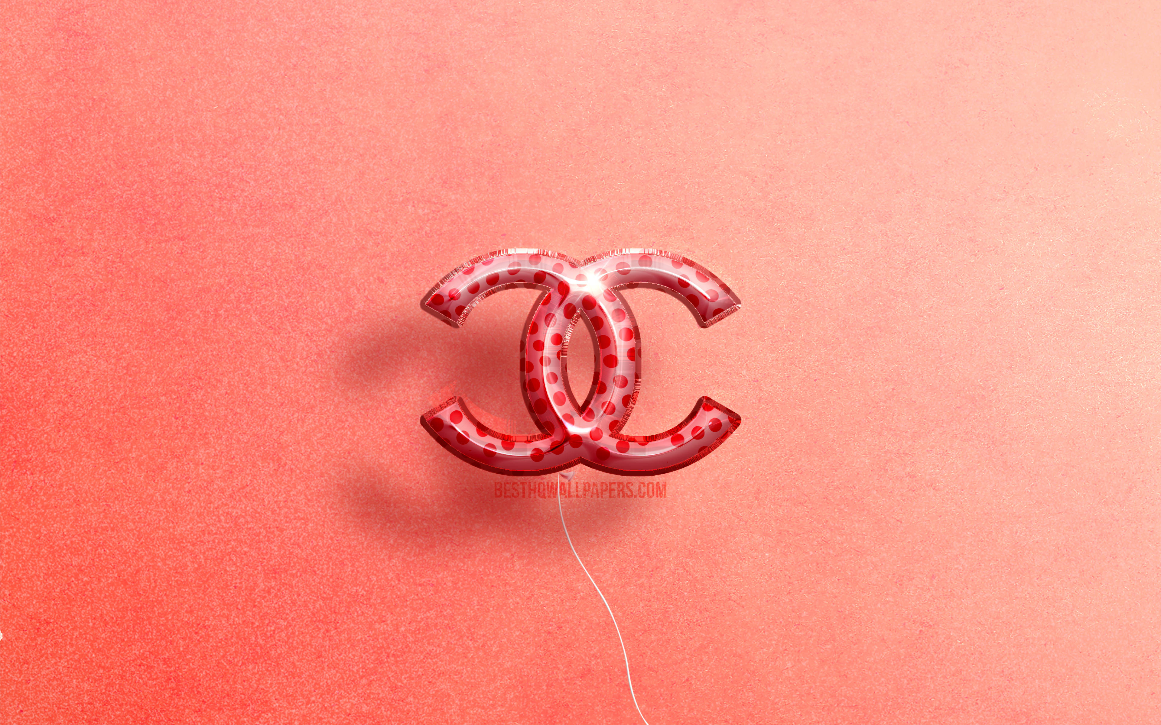 Chanel 桌布 壁紙 — 一個半透明的紅色氣球，形狀像 Chanel 標誌，漂浮在帶有紋理的珊瑚色背景上。