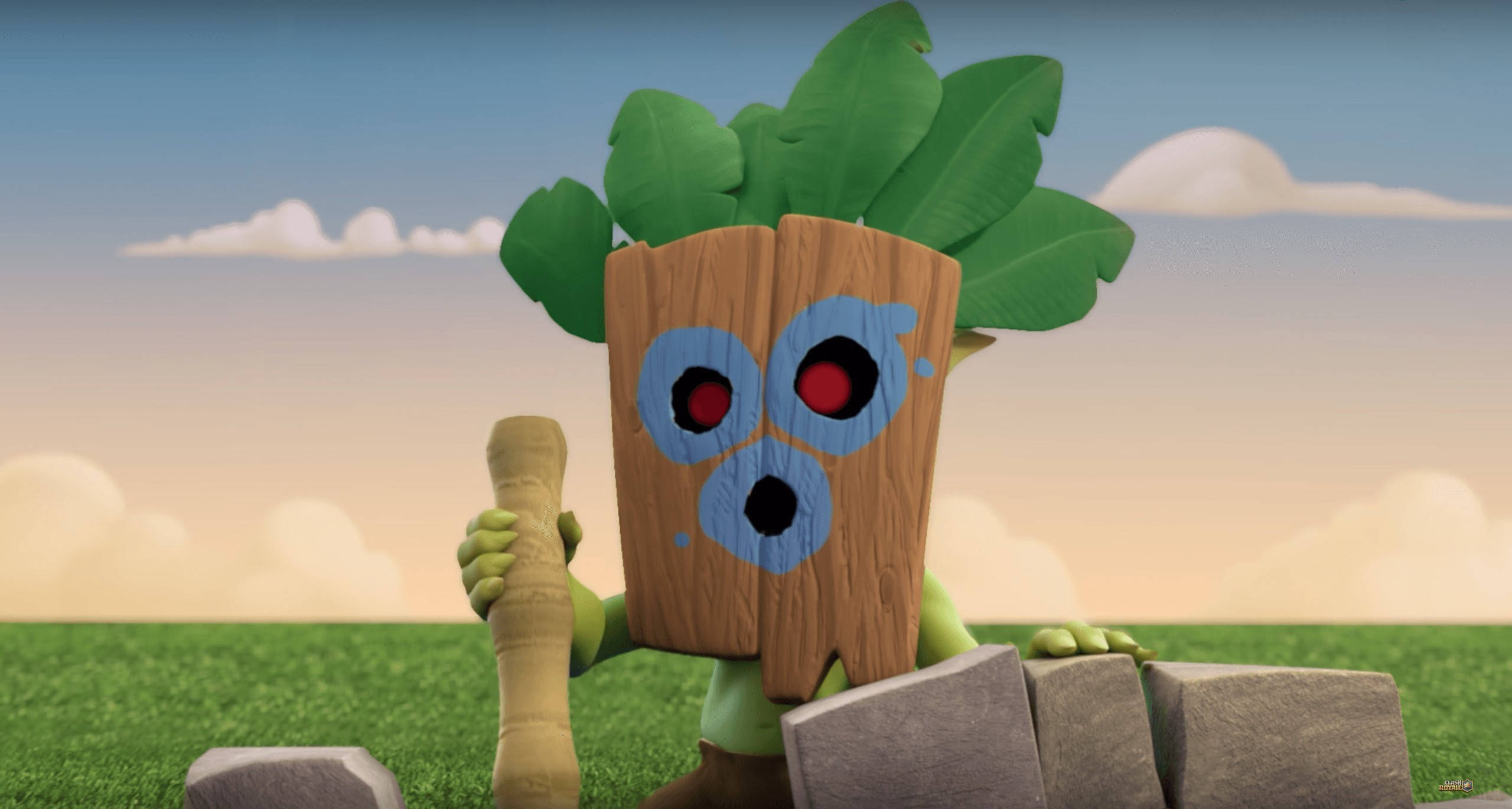 Clash Royale 桌布 壁紙 — 一個卡通樹精靈，有紅色眼睛和綠色葉子，站在草地上，在柔和的天空下，靠近石塊，手持棍棒。