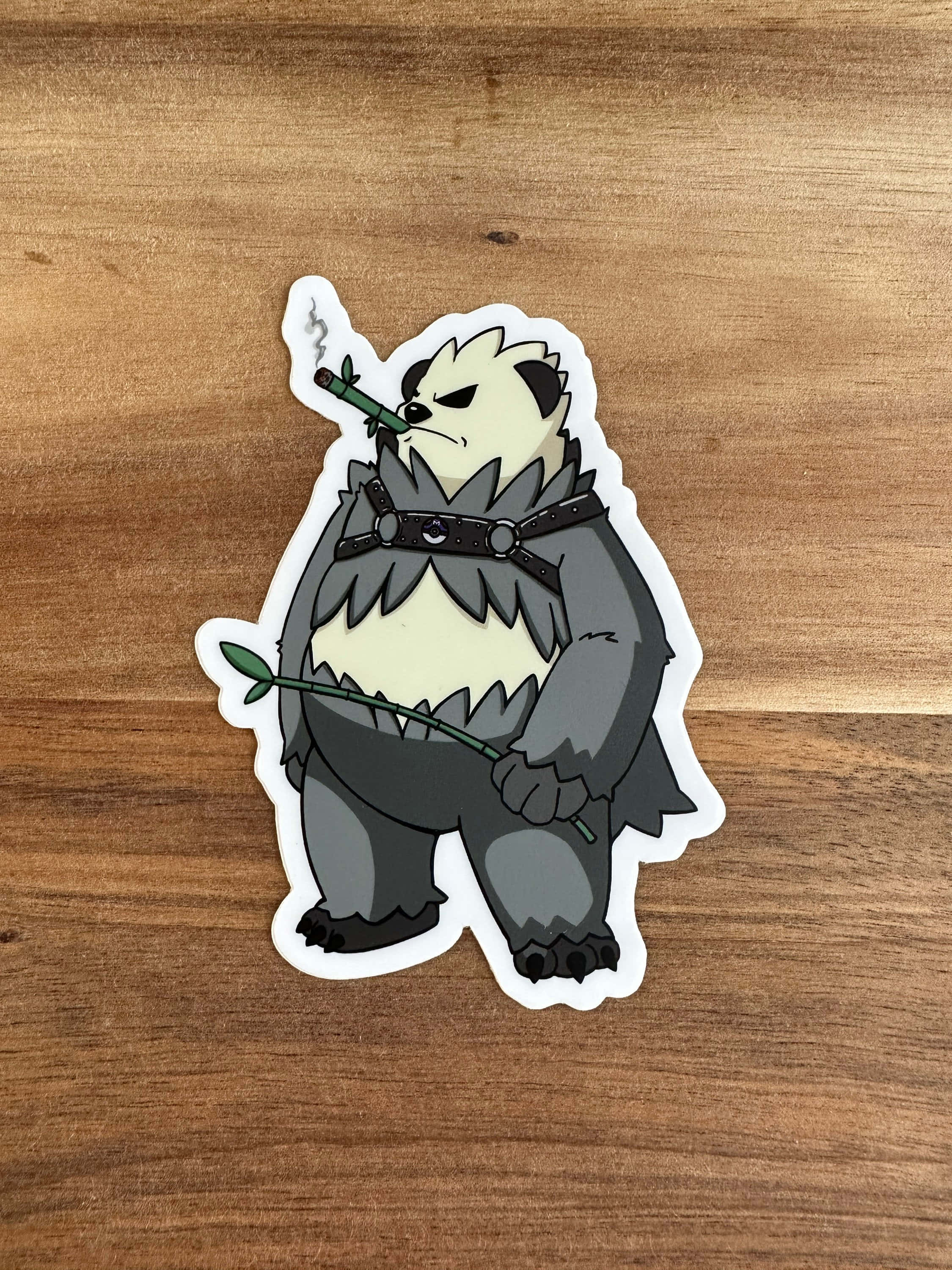 Pokémon 手機 桌布 壁紙 — 一個卡通熊貓戰士貼紙，手持冒煙的竹棍，身穿毛皮盔甲，放在木質表面上。