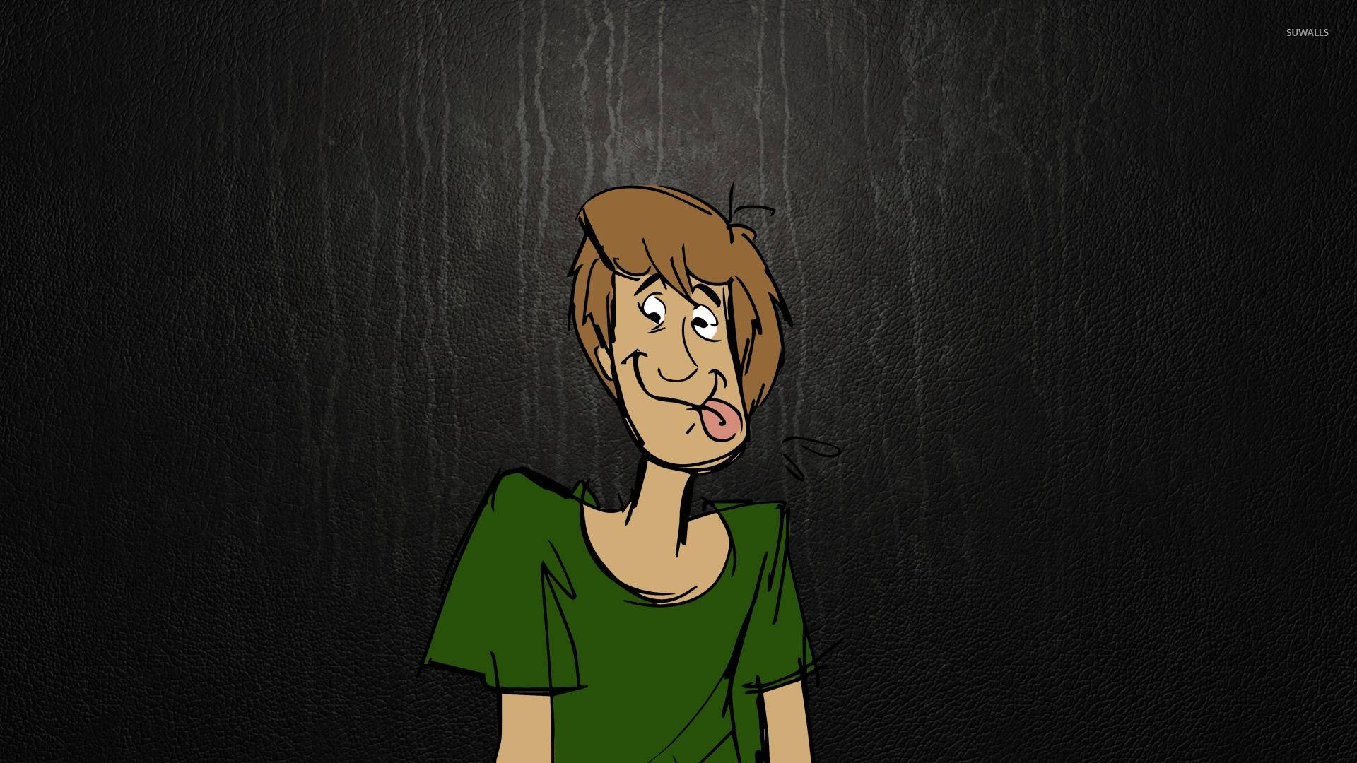 Scooby 桌布 壁紙 — 一個卡通男孩，棕色頭髮，綠色襯衫，在深色紋理背景上伸出舌頭。