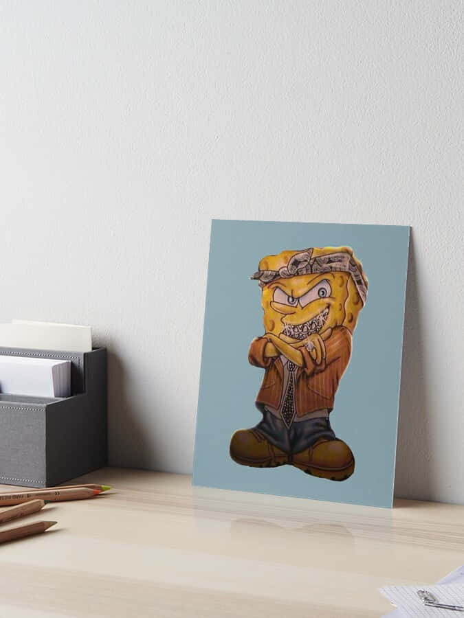 Gangster Spongebob 桌布 壁紙 — 一個卡通風格的黃色海綿角色，表情憤怒，穿著頭巾外套和靴子，靠在桌子上的牆上。