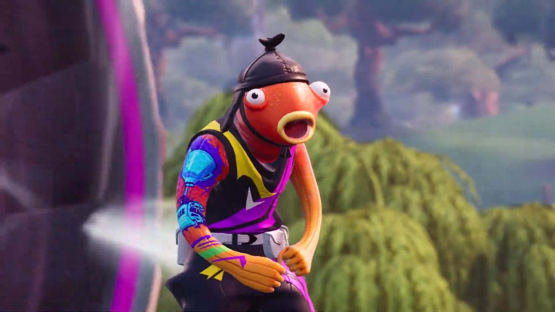 Fortnite Fishstick 桌布 壁紙 — 一個卡通魚角色，戴著黑色帽子，穿著色彩繽紛的服裝，站在充滿活力的戶外場景中，周圍有綠色植物和紫色燈光效果。