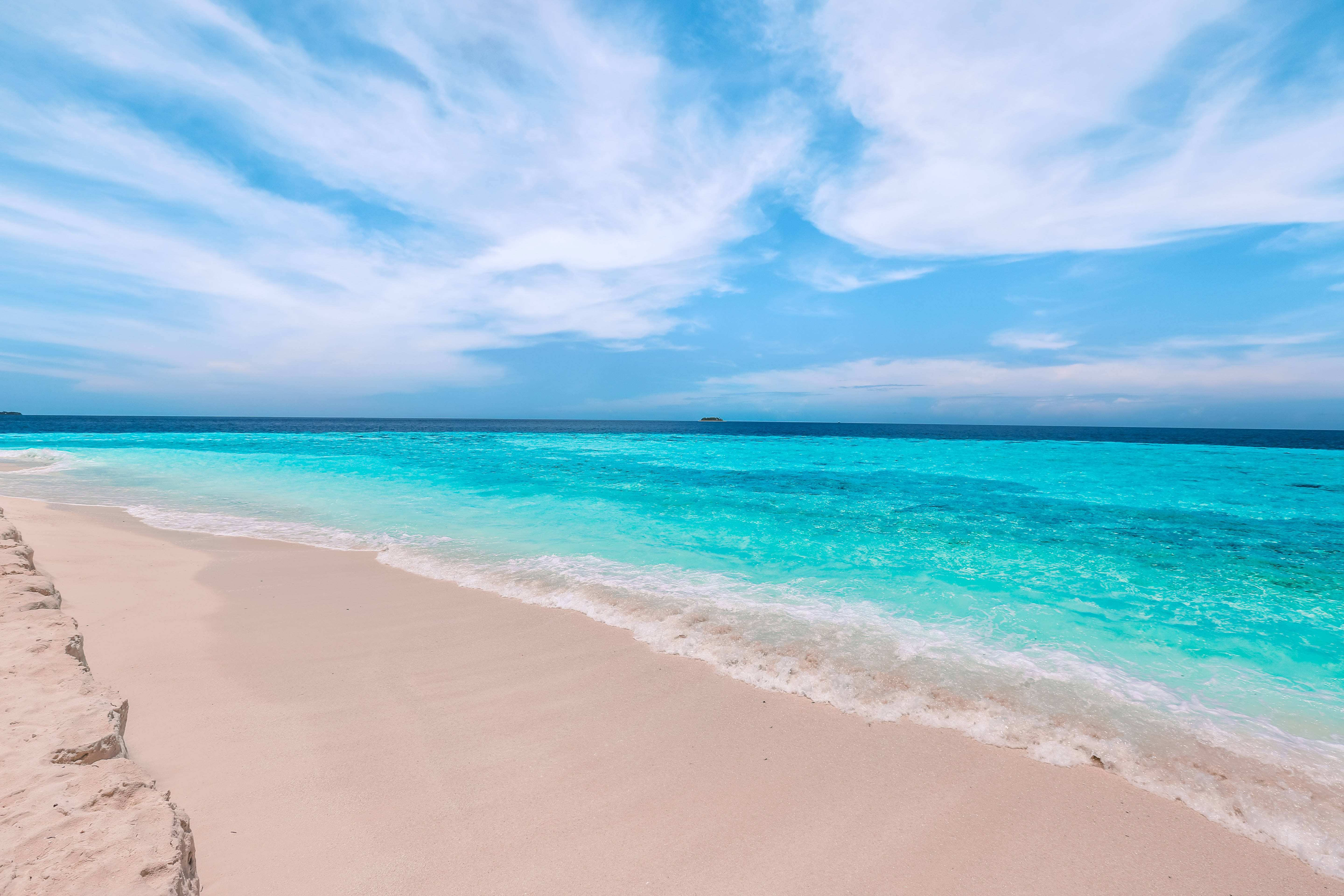 sand 桌布 壁紙 — 一個原始熱帶海灘，碧綠的海水輕輕拍打柔軟的粉紅色沙灘，明亮的藍天下有縷縷白雲。