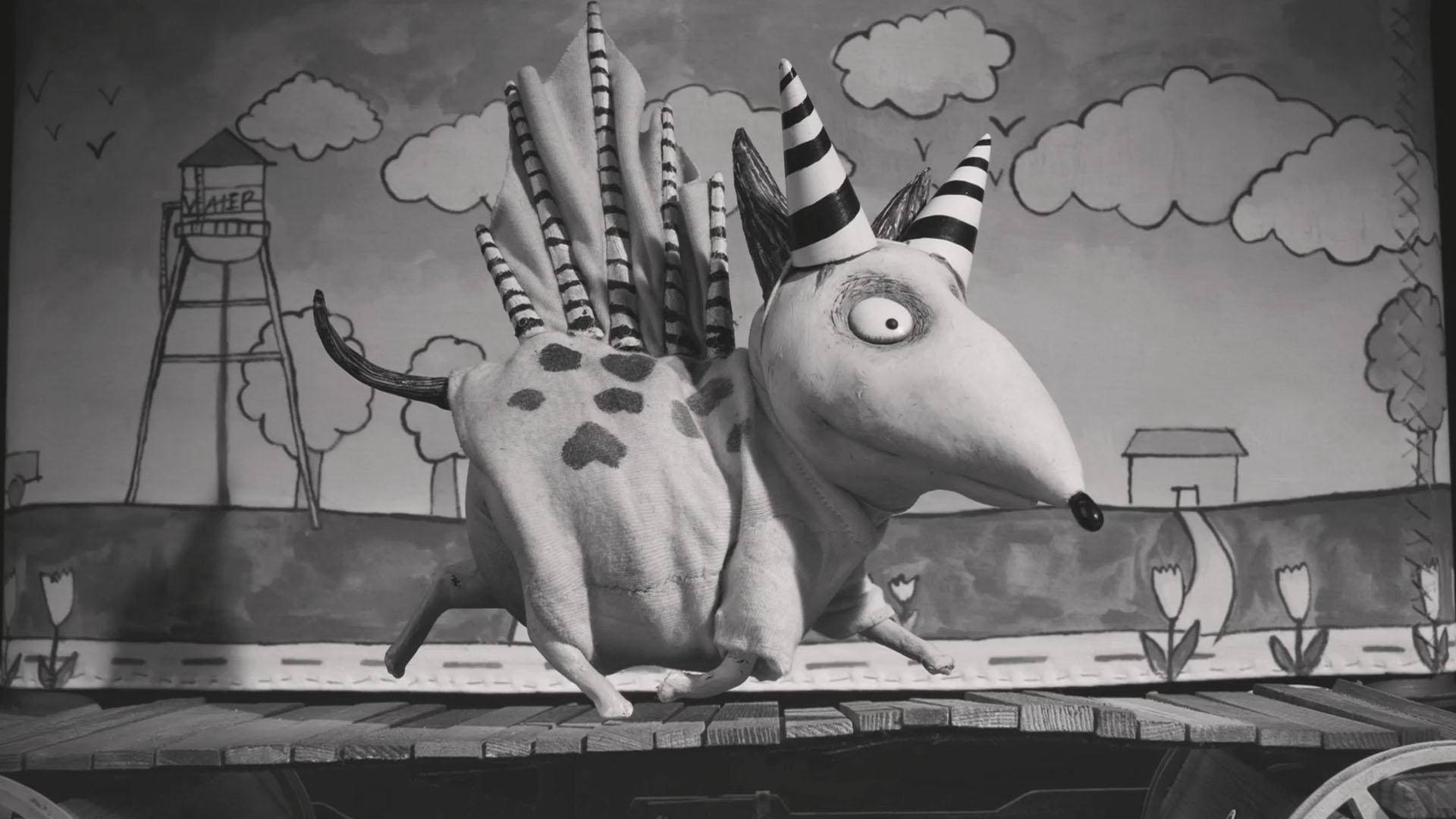 Frankenweenie 桌布 壁紙 — 一個古怪的黑白定格動畫生物，帶有條紋角和刺，在木製平台上奔跑，背景是手繪的。