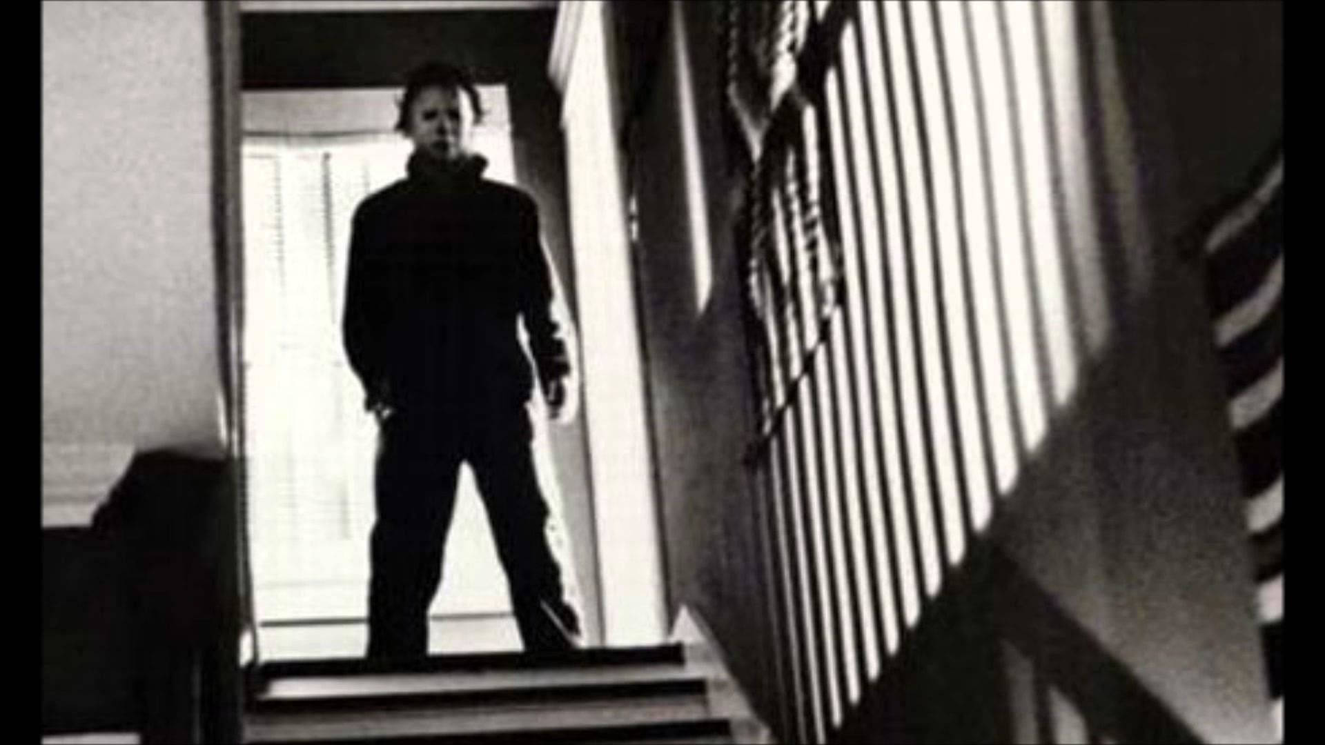 michael 桌布 壁紙 — 一個可怕的身影站在昏暗的樓梯頂端，垂直百葉窗投射出鮮明的陰影。
