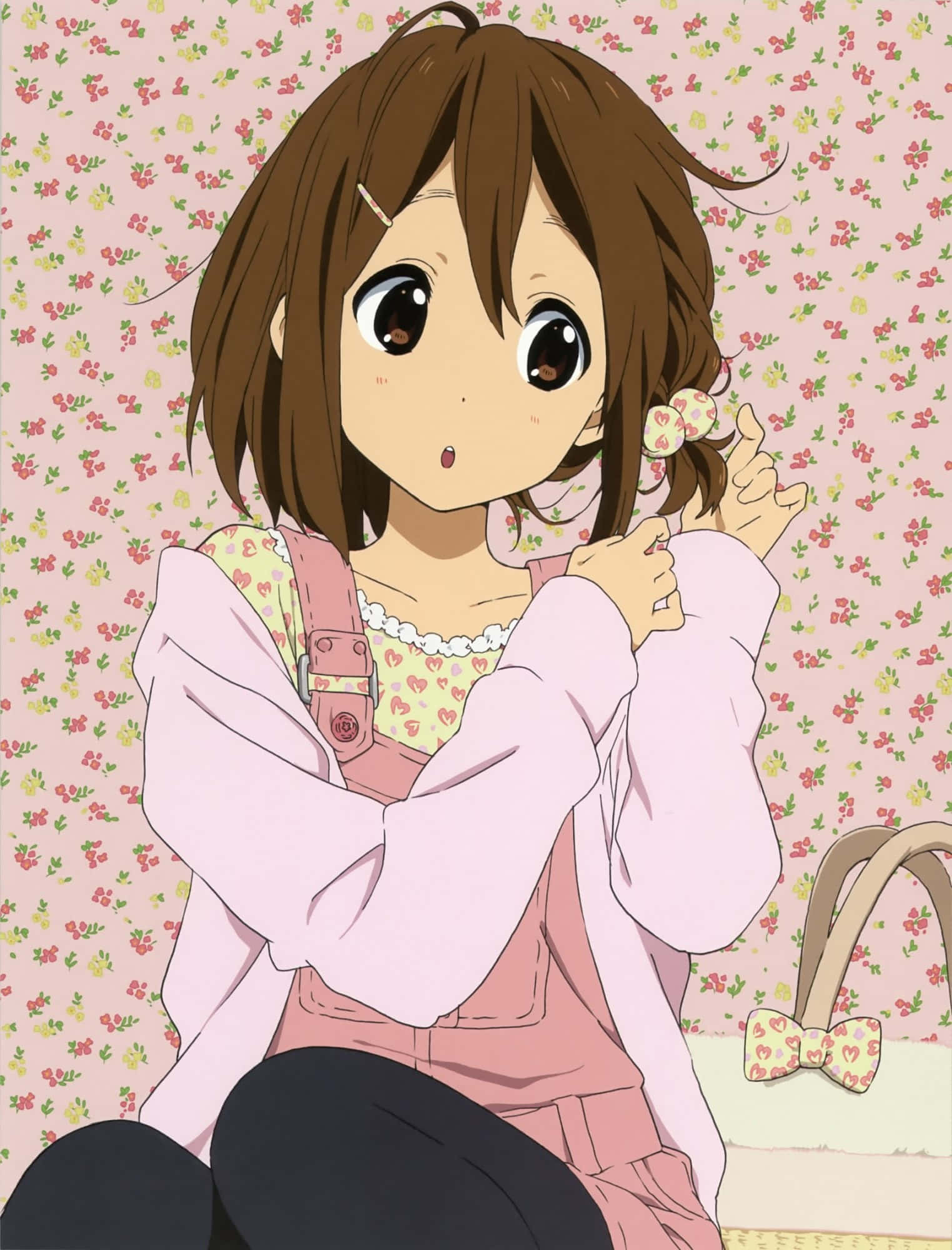 yui hirasawa 桌布 壁紙 — 一個可愛的動漫女孩，棕色頭髮和大眼睛，坐在粉紅色花卉壁紙前，穿著粉紅色服裝，手持一朵花。