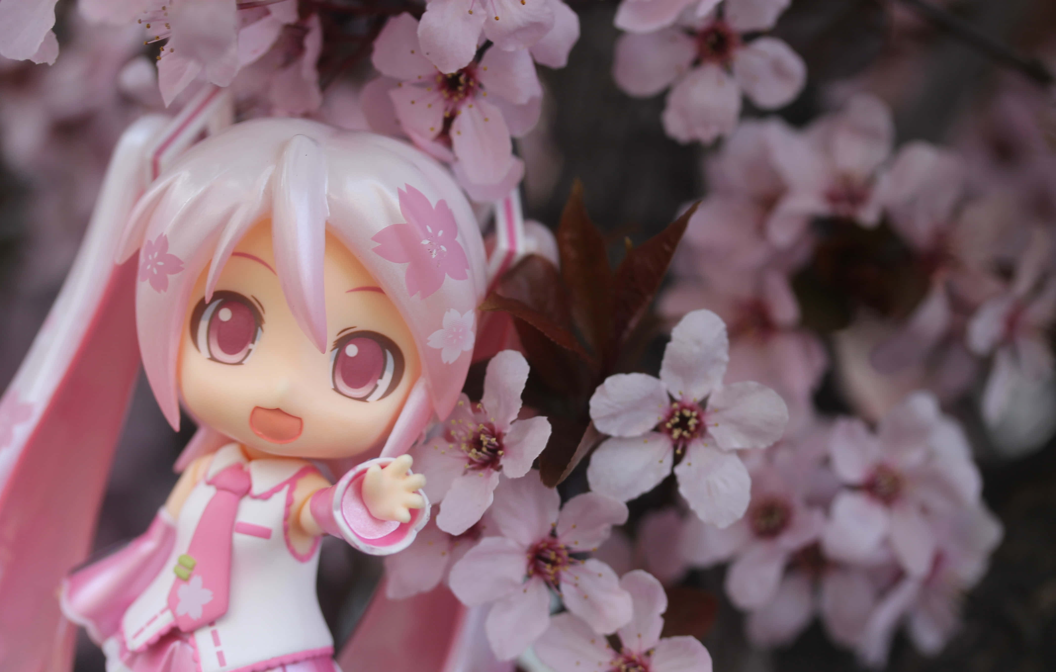 Vocaloid 桌布 壁紙 — 一個可愛的粉紅色頭髮動漫人偶站在柔和的粉紅色櫻花中，帶著溫柔的微笑。