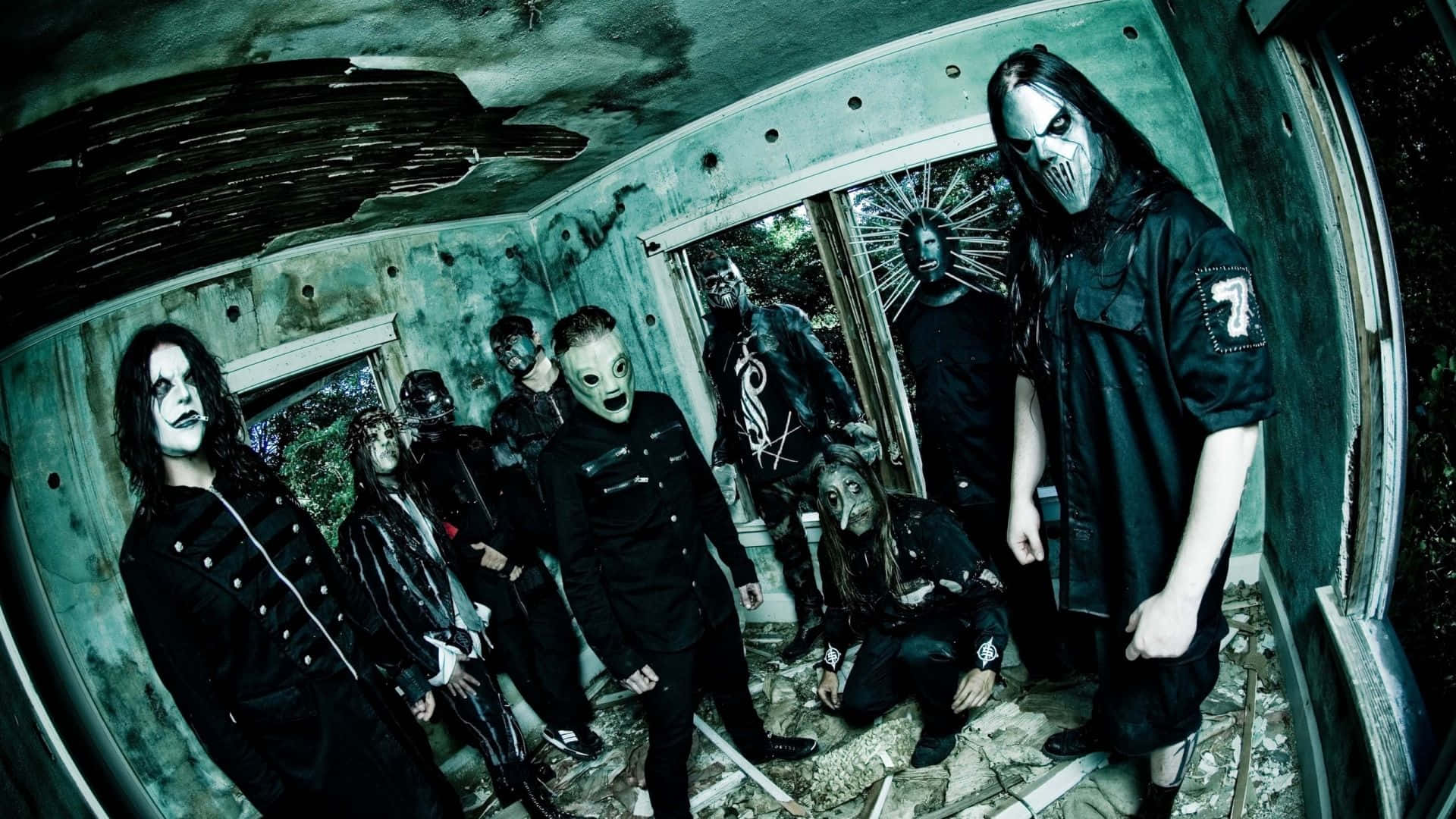 Slipknot 桌布 壁紙 — 一個哥德金屬樂團，化著蒼白的妝容，穿著黑色服裝，在一個破舊、魚眼鏡頭扭曲的房間裡擺出威脅性的姿勢。