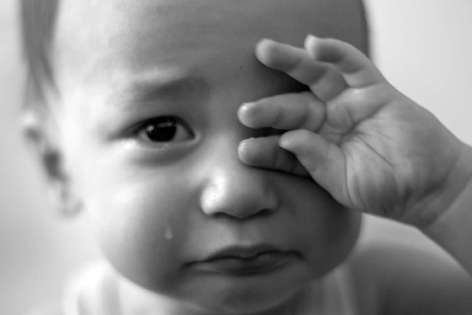 Emotional 桌布 壁紙 — 一個哭泣嬰兒的黑白特寫，一隻手遮住半邊臉，淚水順著臉頰流下。