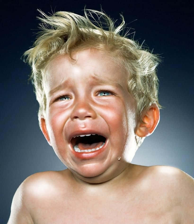 cry 桌布 壁紙 — 一個哭泣幼兒的特寫，一頭凌亂的金色頭髮，臉頰上掛著淚痕，背景是深藍色。