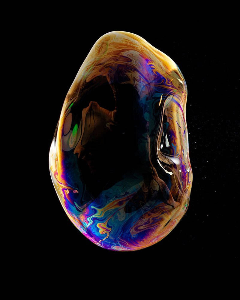 iPhone XS 桌布 壁紙 — 一個單一的彩虹色肥皂泡在佈滿星星的黑色虛空中漂浮，旋轉著鮮豔的彩虹色調。