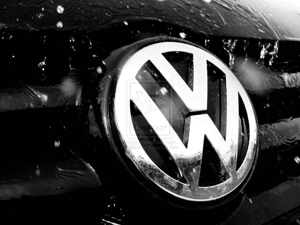 福斯汽車 桌布 壁紙 — 一個單色特寫，濕潤的 Volkswagen 標誌在汽車引擎蓋上閃閃發光，帶有水珠和飛濺。
