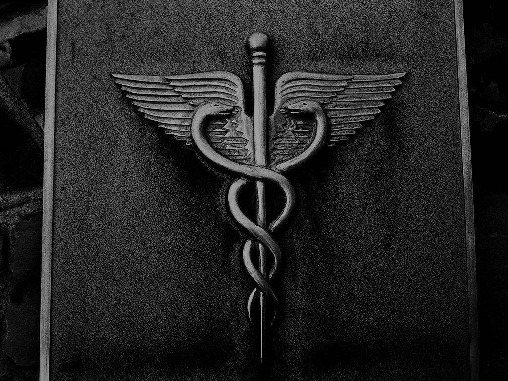 medical motivation 桌布 壁紙 — 一個單色特寫，詳細的醫療符號卡杜修斯雕刻在深色紋理石面上。