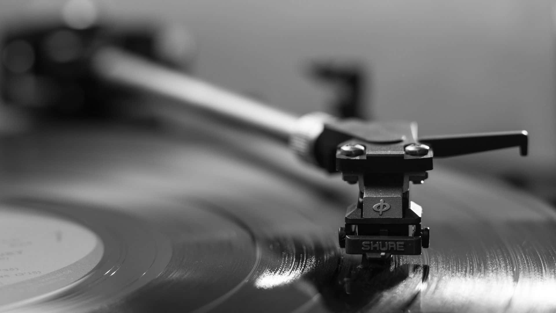 Black And White Music 桌布 壁紙 — 一個單色特寫，顯示Shure唱頭輕輕擱在旋轉的黑膠唱片溝槽上。