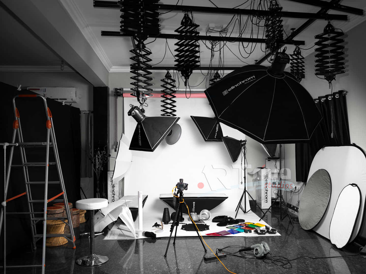 Photo Studio 桌布 壁紙 — 一個單色調的專業攝影工作室，反射性地板上佈滿照明設備和器材。
