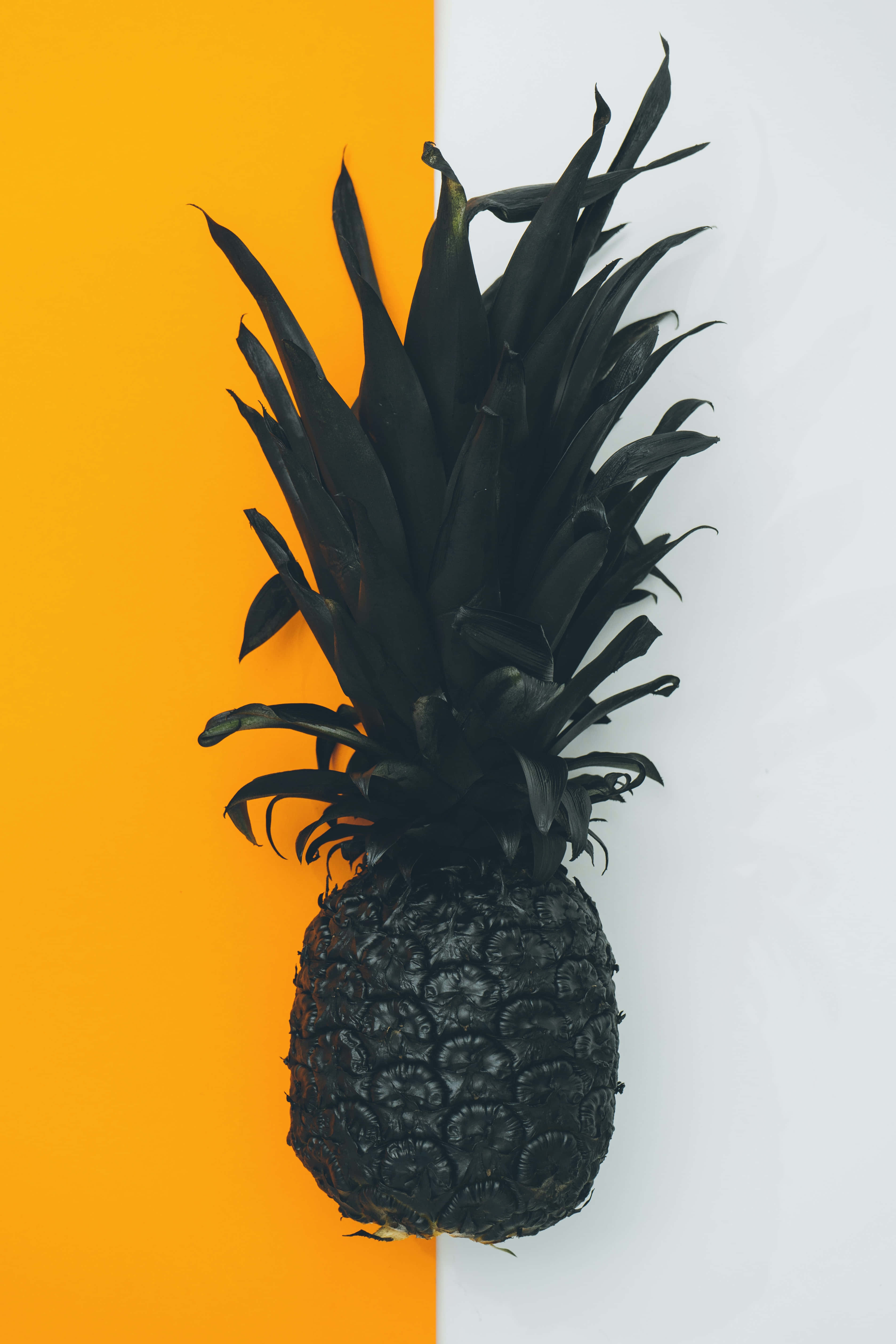Pineapple 桌布 壁紙 — 一個單色黑色鳳梨居中於大膽分割的橙色和白色背景上。