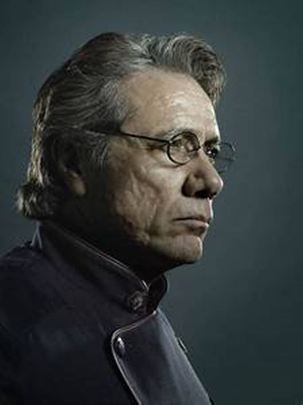 actor 桌布 壁紙 — 一個嚴肅的中年男子戴著眼鏡，頭髮花白，側面特寫，背景為深灰色。