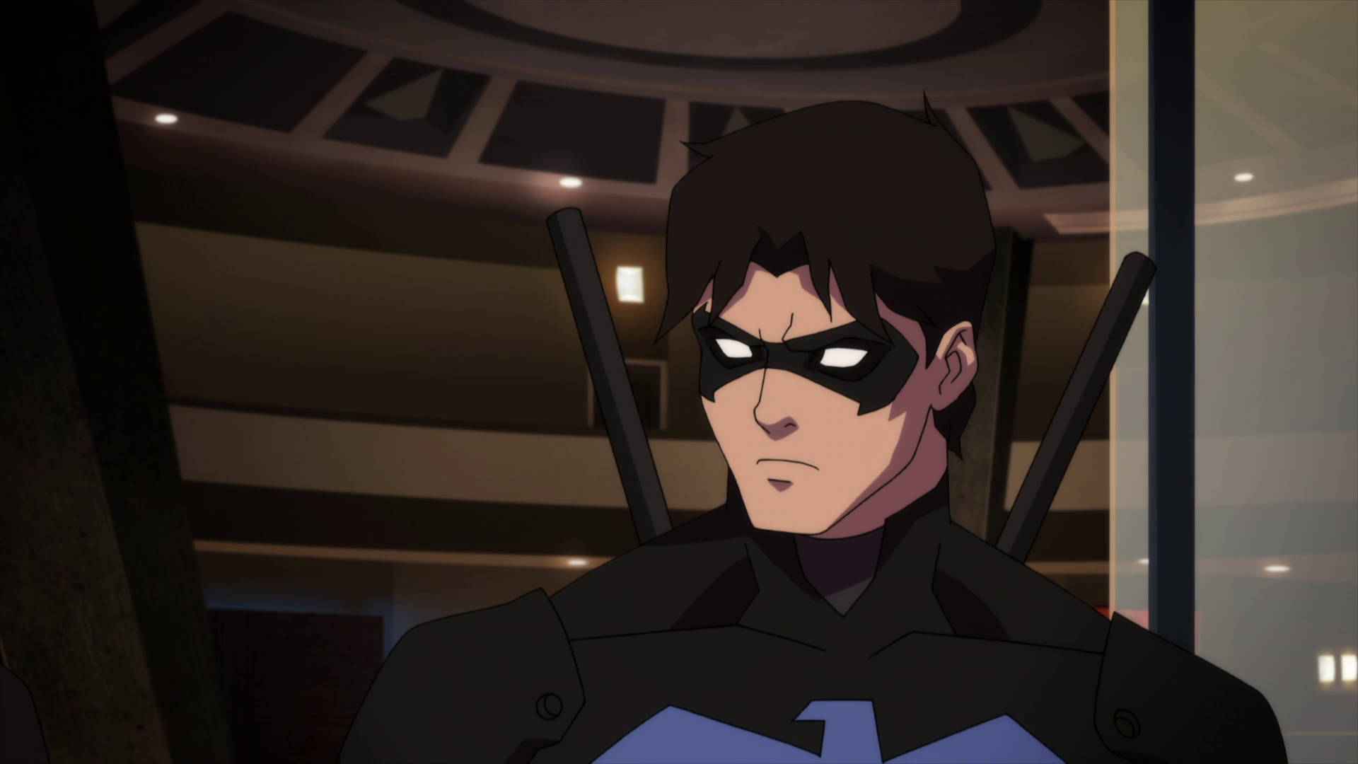 Young Justice 桌布 壁紙 — 一個嚴肅的動畫義警，身穿黑色西裝，帶有藍色蝙蝠標誌，室內站立，背上有一對警棍。